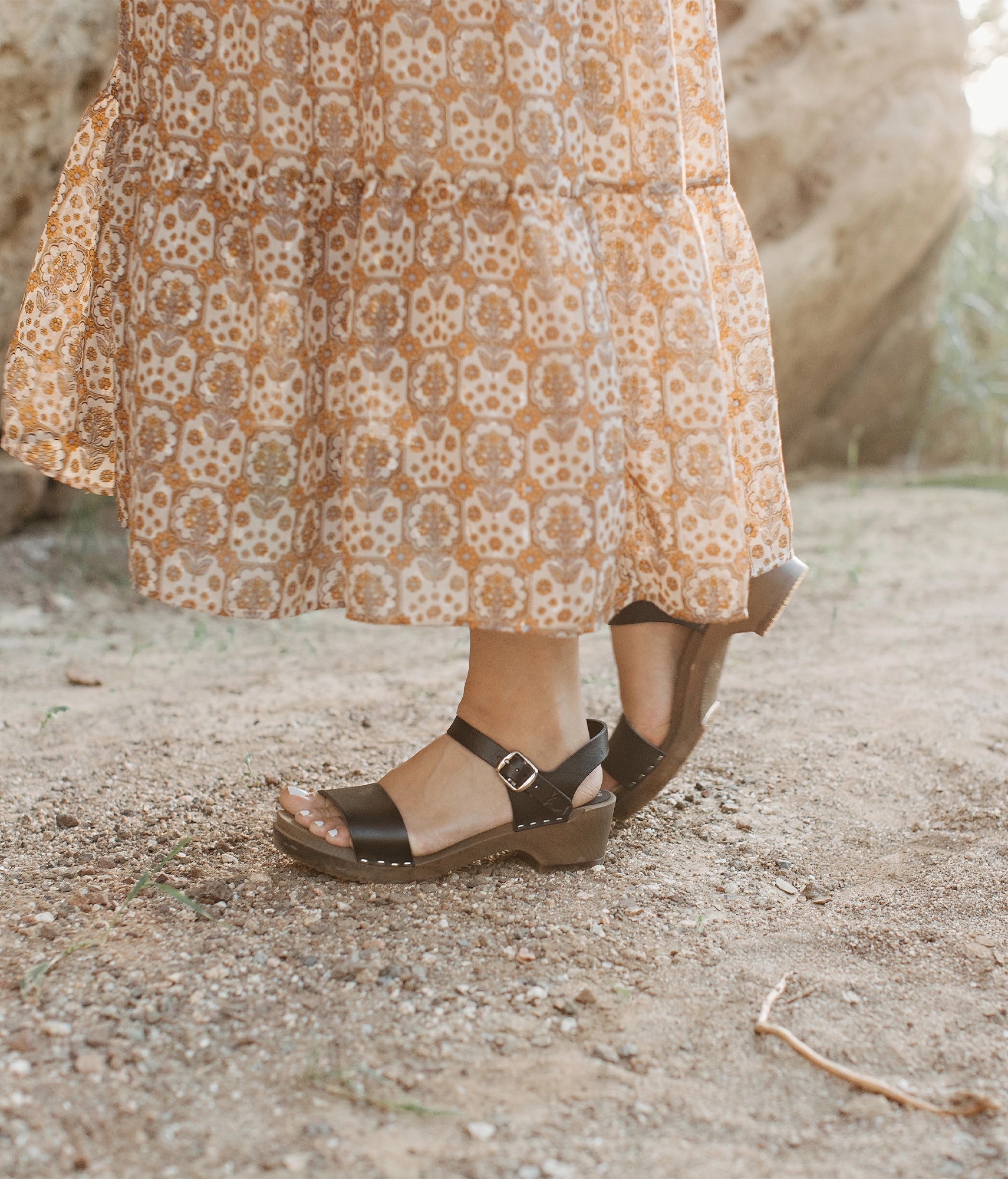 low heeled open-toe clog sandal in black vegetable tanned leather stapled on a dark wooden base