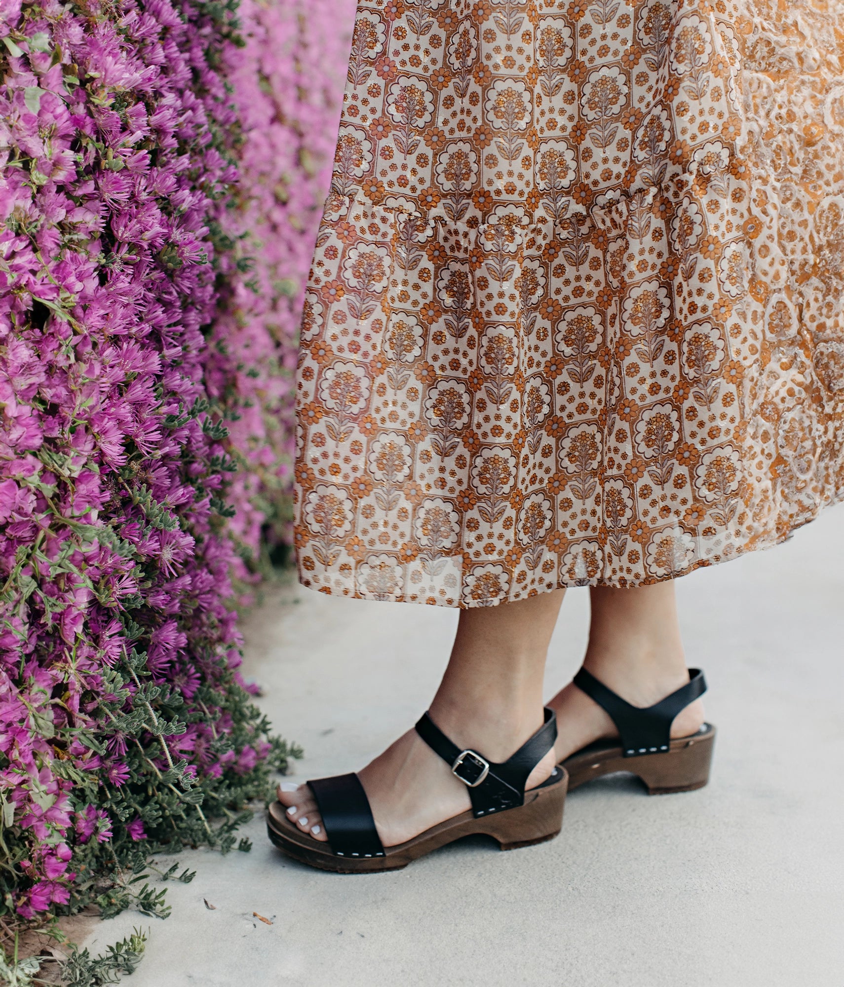 low heeled open-toe clog sandal in black vegetable tanned leather stapled on a dark wooden base