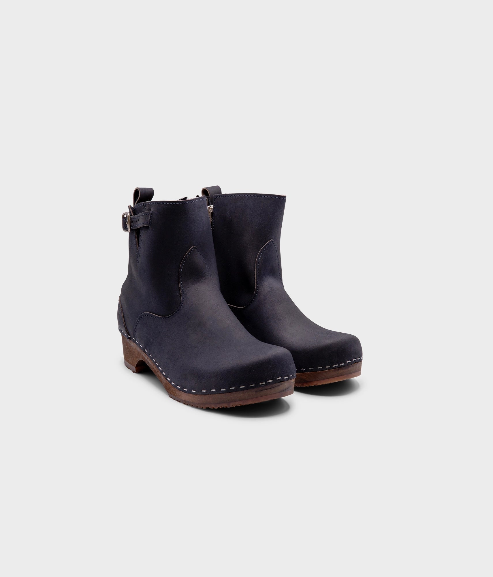 low heeled clog boots in navy blue nubuck leather with a mid-shaft and silver buckle, stapled on a dark wooden base
