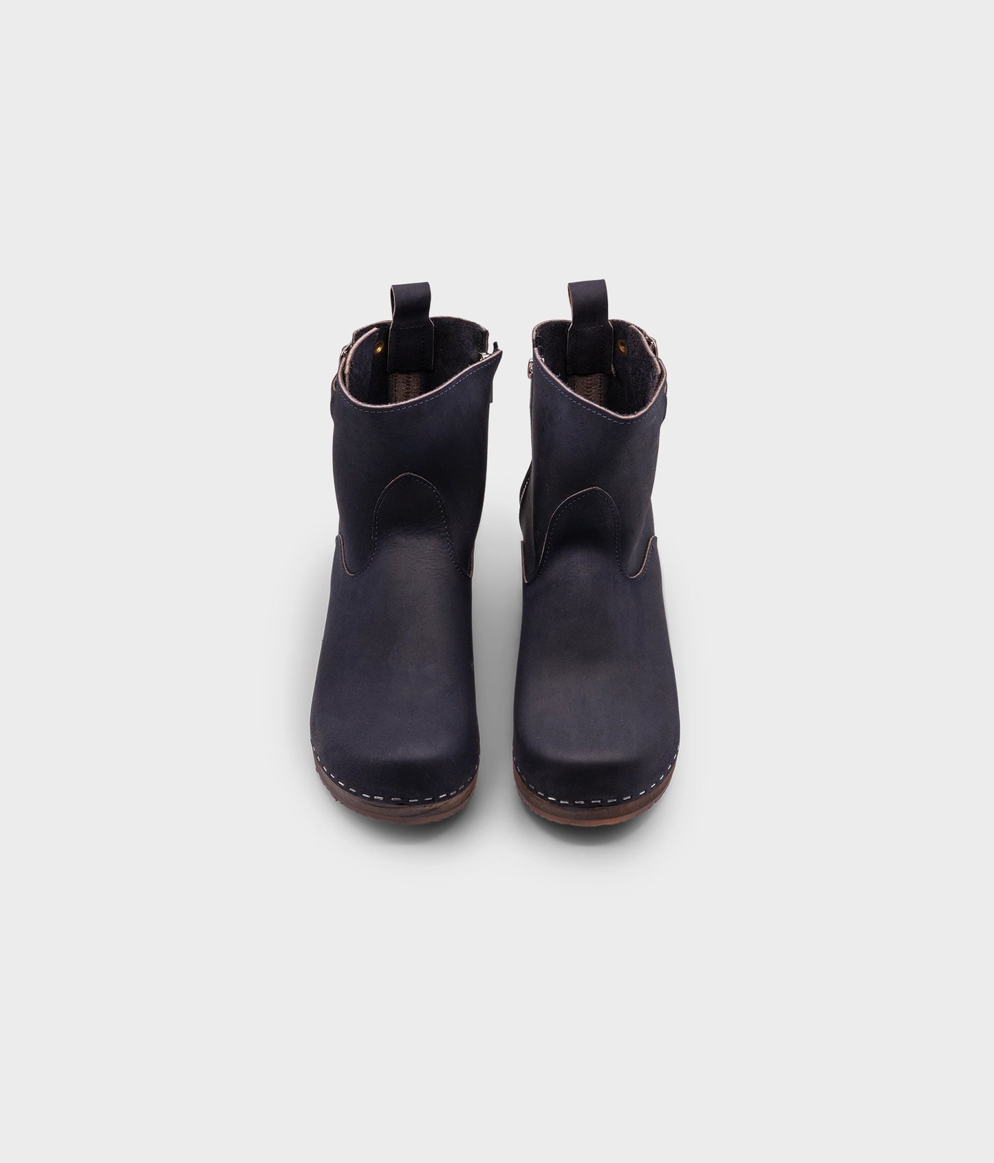 low heeled clog boots in navy blue nubuck leather with a mid-shaft and silver buckle, stapled on a dark wooden base
