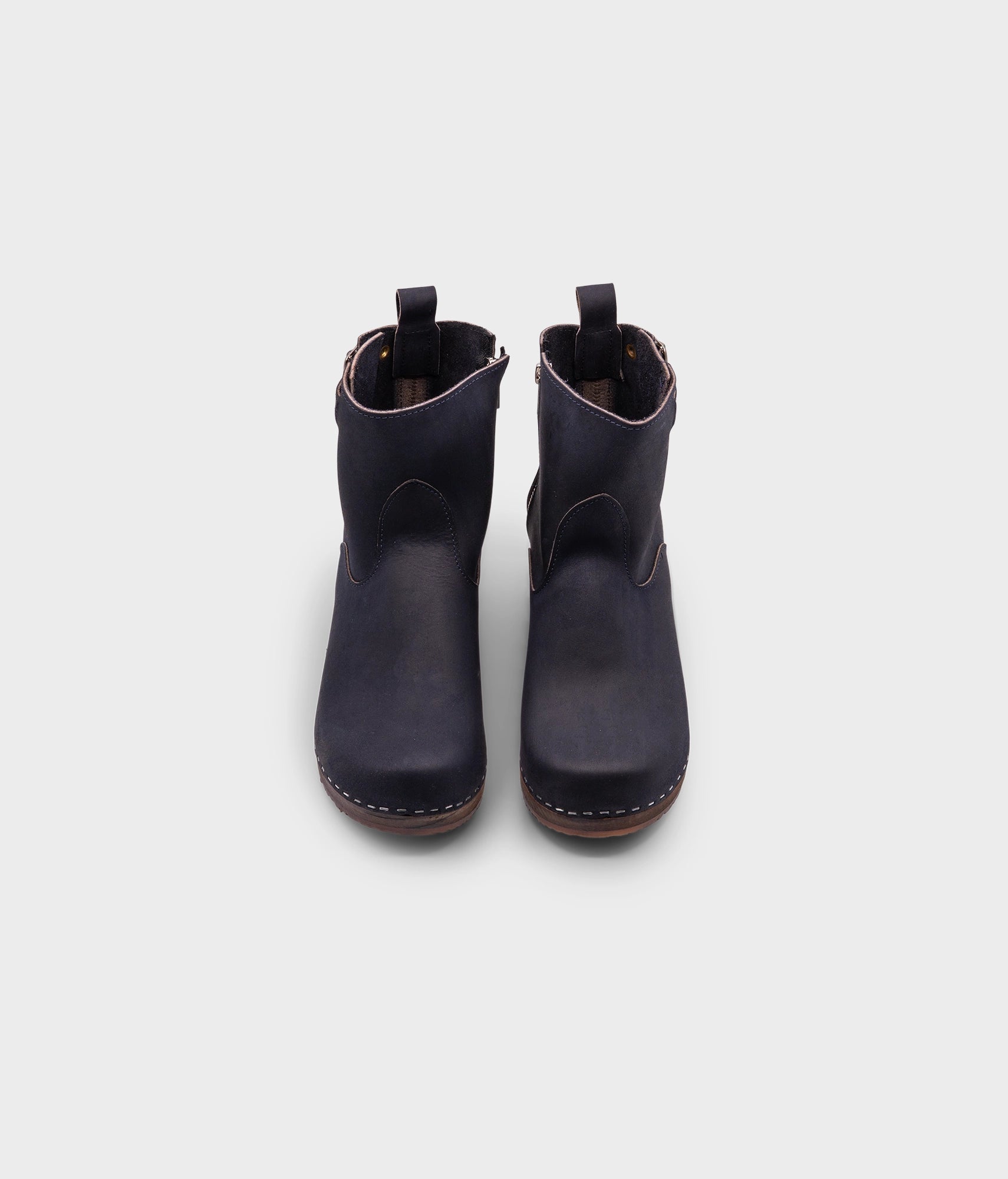 low heeled clog boots in navy blue nubuck leather with a mid-shaft and silver buckle, stapled on a dark wooden base