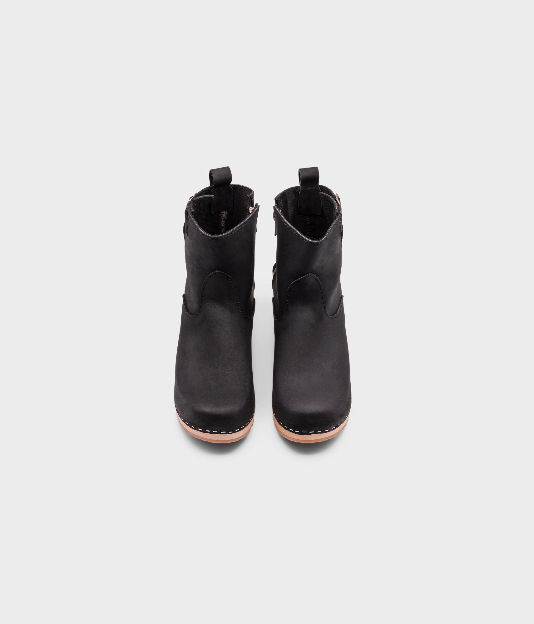 high-heeled clog boots in black nubuck leather stapled on a light wooden base with a silver buckle