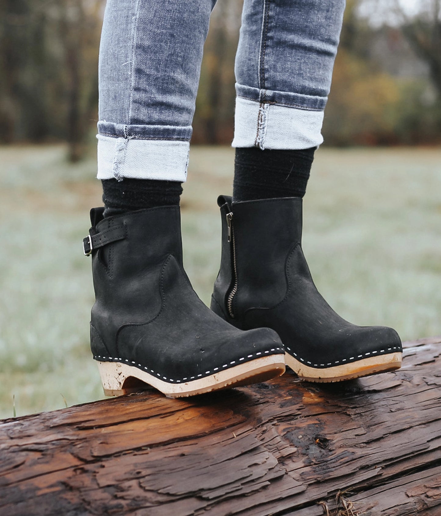 low-heeled clog boots in black nubuck  leather stapled on a light wooden base