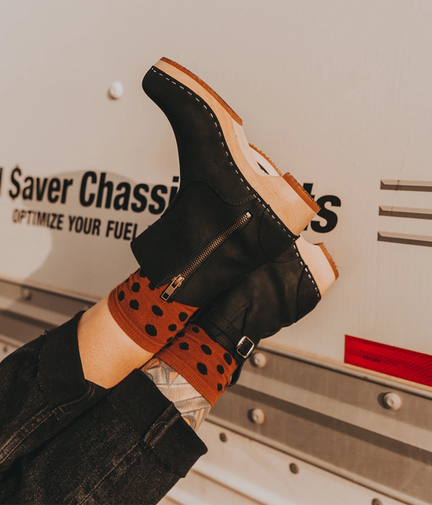 Women wearing low-heeled clog boots in black nubuck  leather stapled on a light wooden base