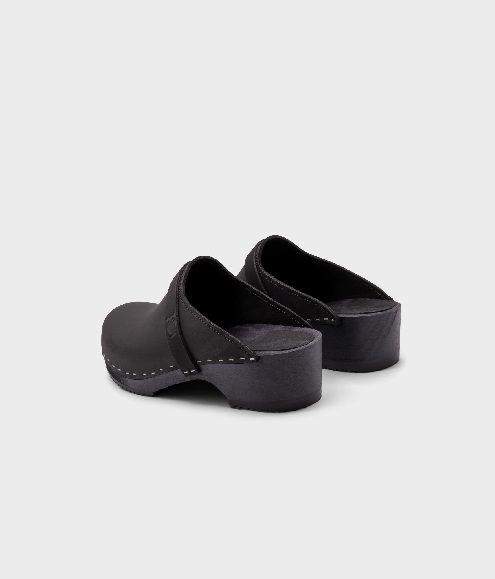 classic low heeled clog mule in black nubuck leather stapled on a black wooden base with a leather strap