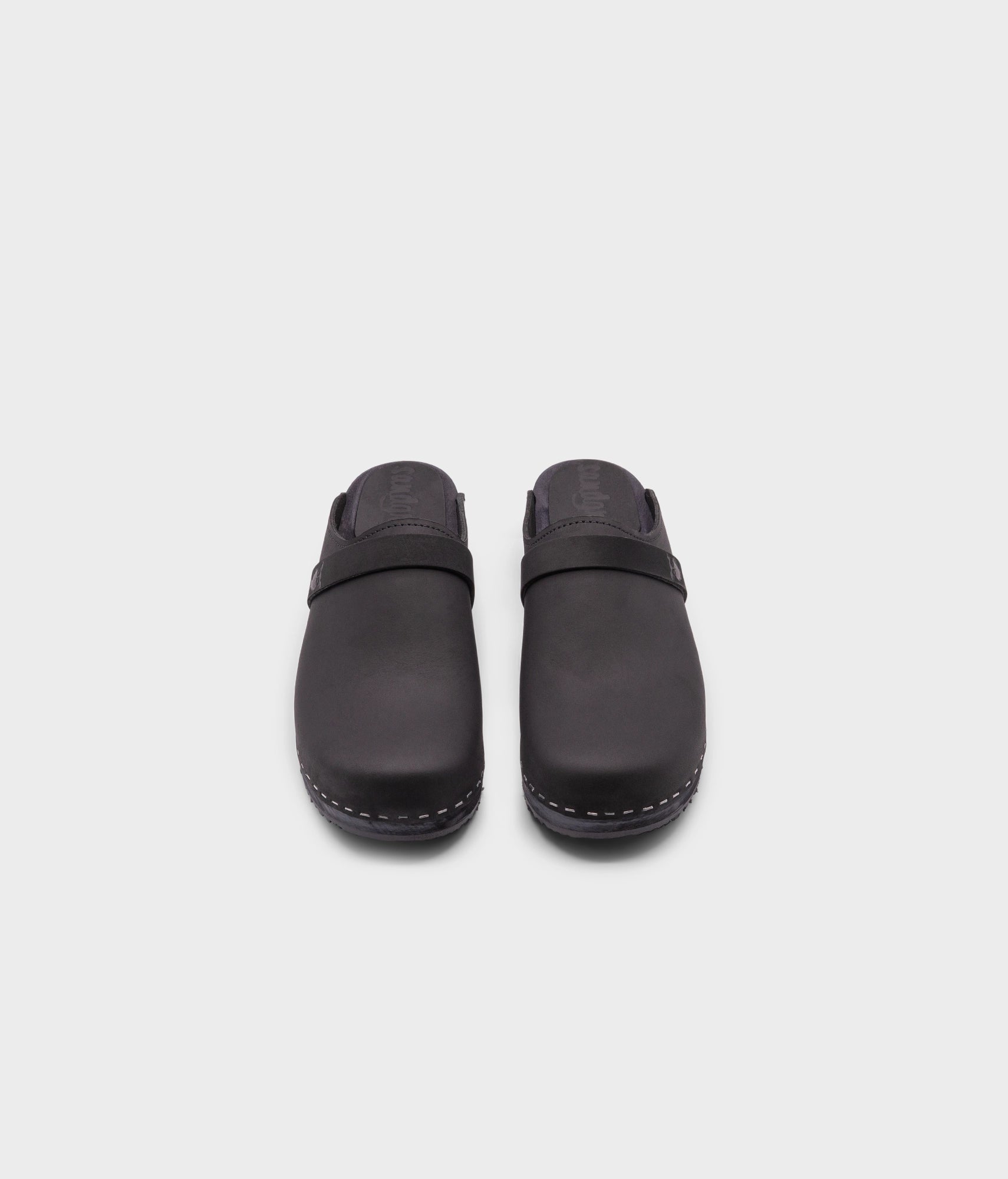 classic low heeled clog mule in black nubuck leather stapled on a black wooden base with a leather strap