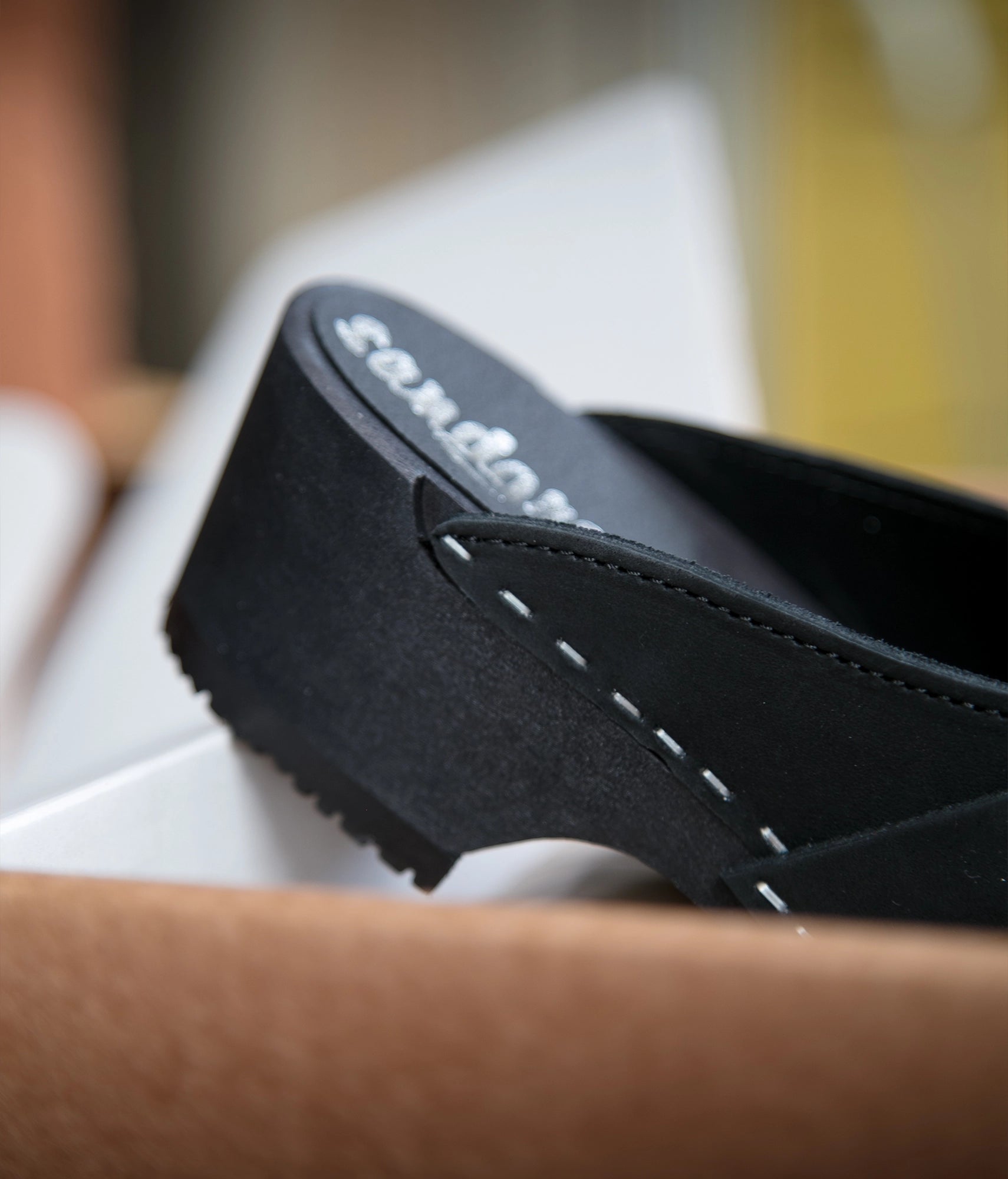 classic low heeled clog mule in black nubuck leather stapled on a black wooden base with a leather strap