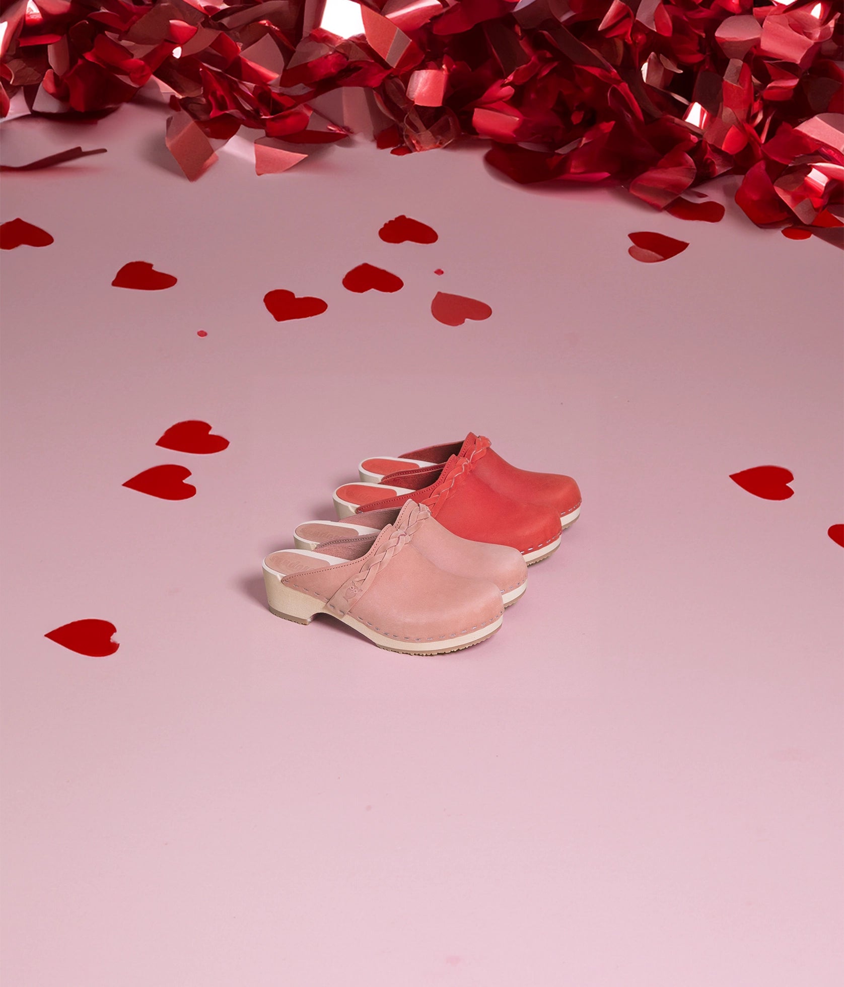 low heeled clog mules in blush pink nubuck leather with a braided strap stapled on a light wooden base