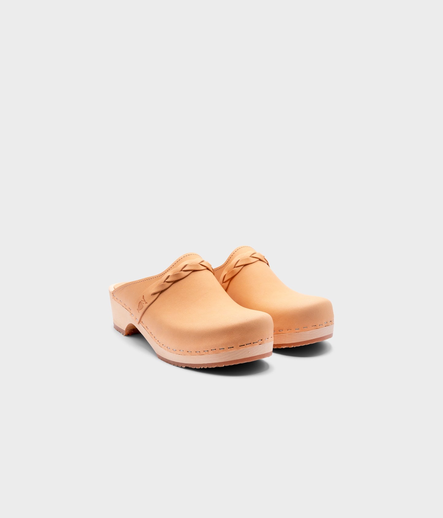 low heeled clog mules in ecru beige vegetable tanned leather with a braided strap stapled on a light wooden base