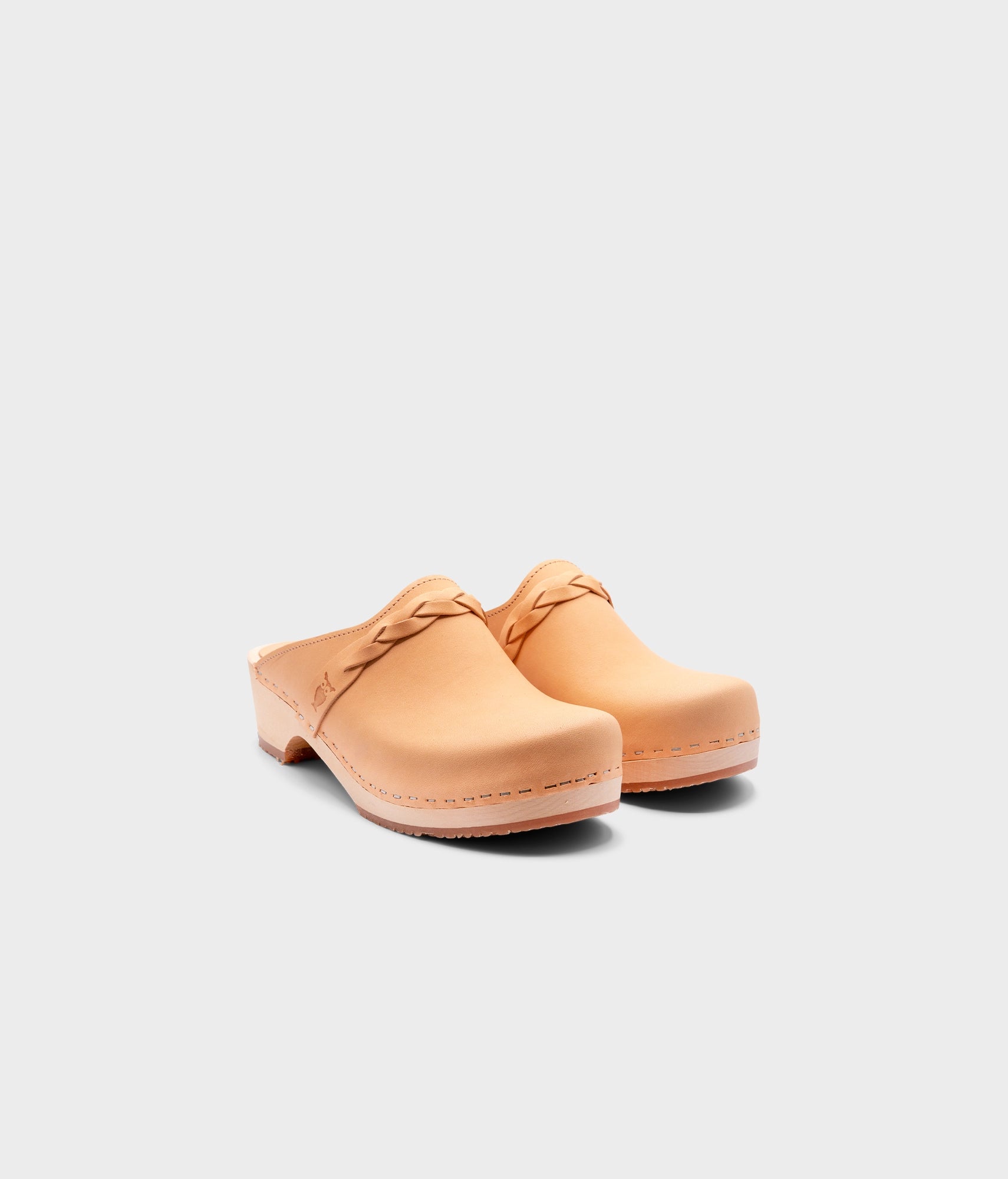 low heeled clog mules in ecru beige vegetable tanned leather with a braided strap stapled on a light wooden base
