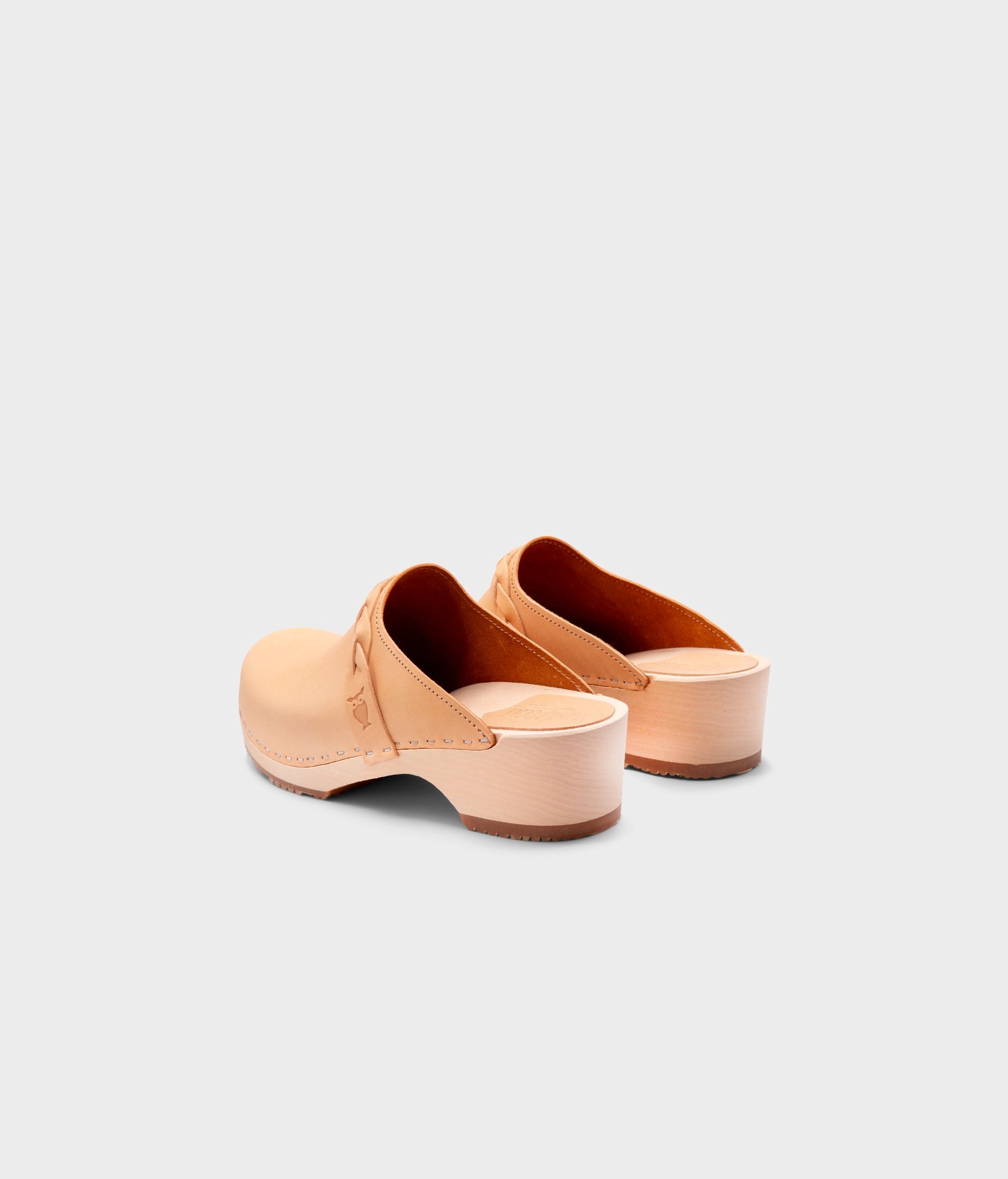 low heeled clog mules in ecru beige vegetable tanned leather with a braided strap stapled on a light wooden base