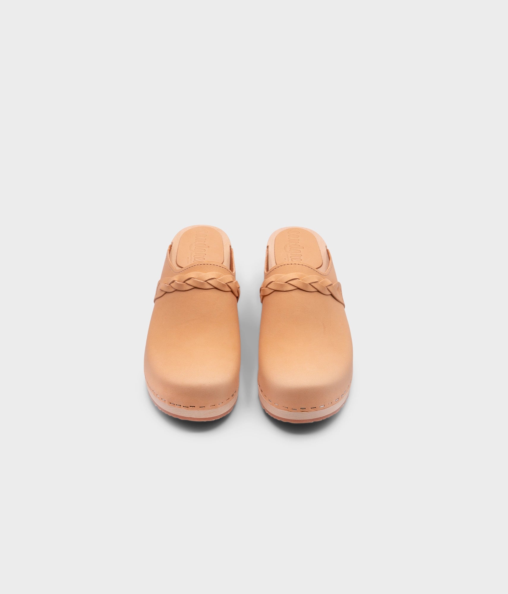low heeled clog mules in ecru beige vegetable tanned leather with a braided strap stapled on a light wooden base