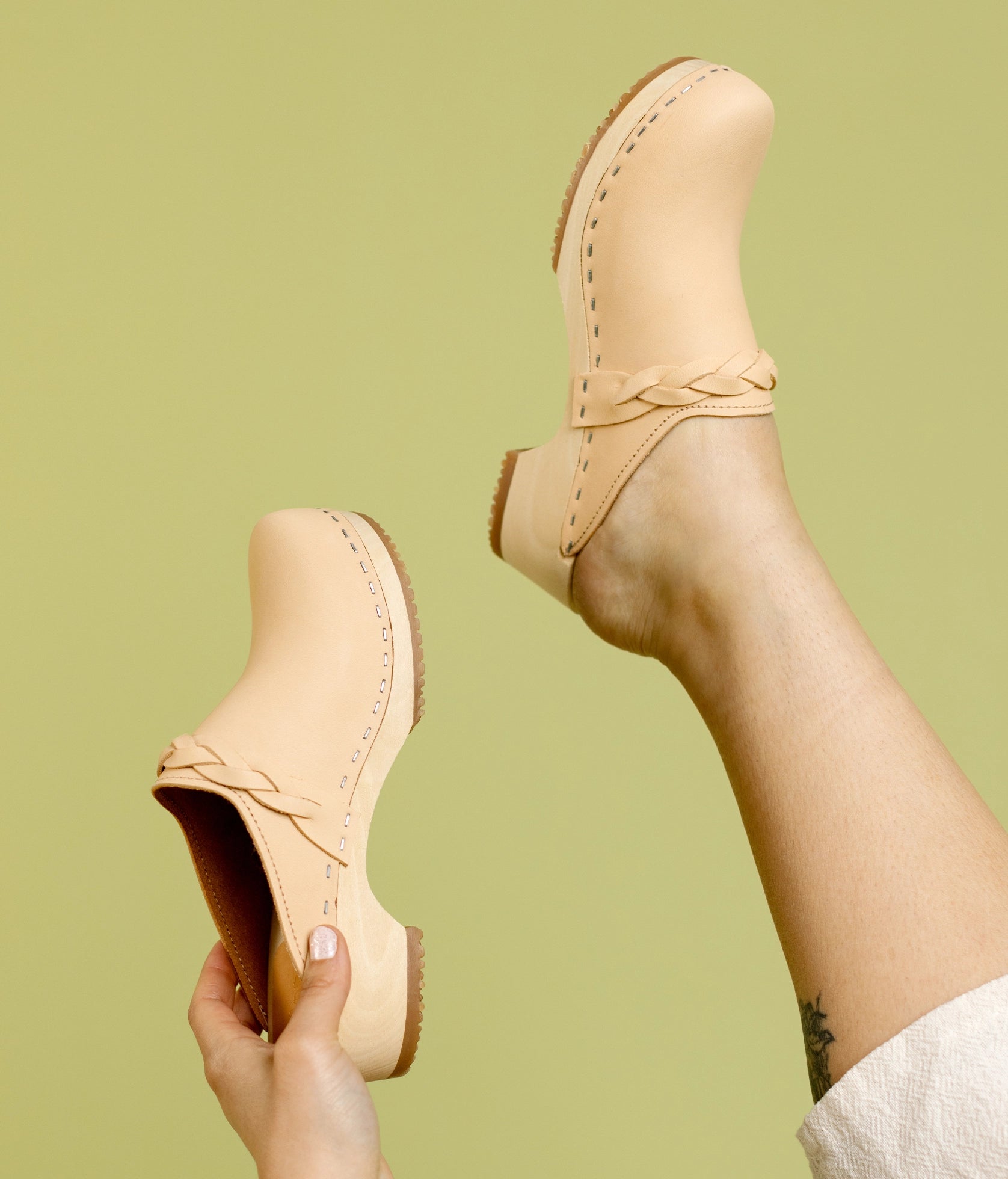 low heeled clog mules in ecru beige vegetable tanned leather with a braided strap stapled on a light wooden base