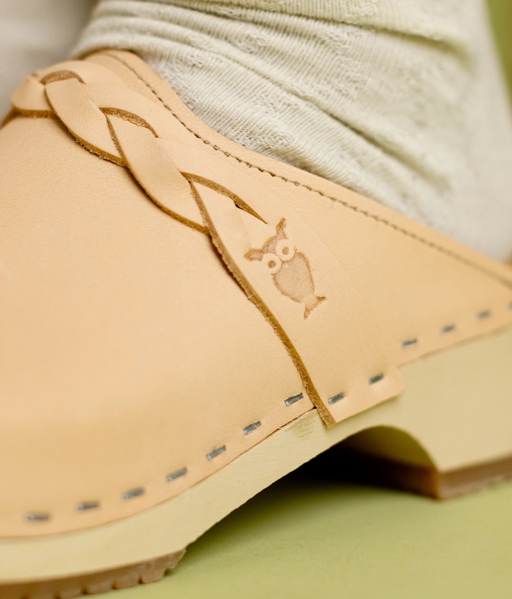 low heeled clog mules in ecru beige vegetable tanned leather with a braided strap stapled on a light wooden base