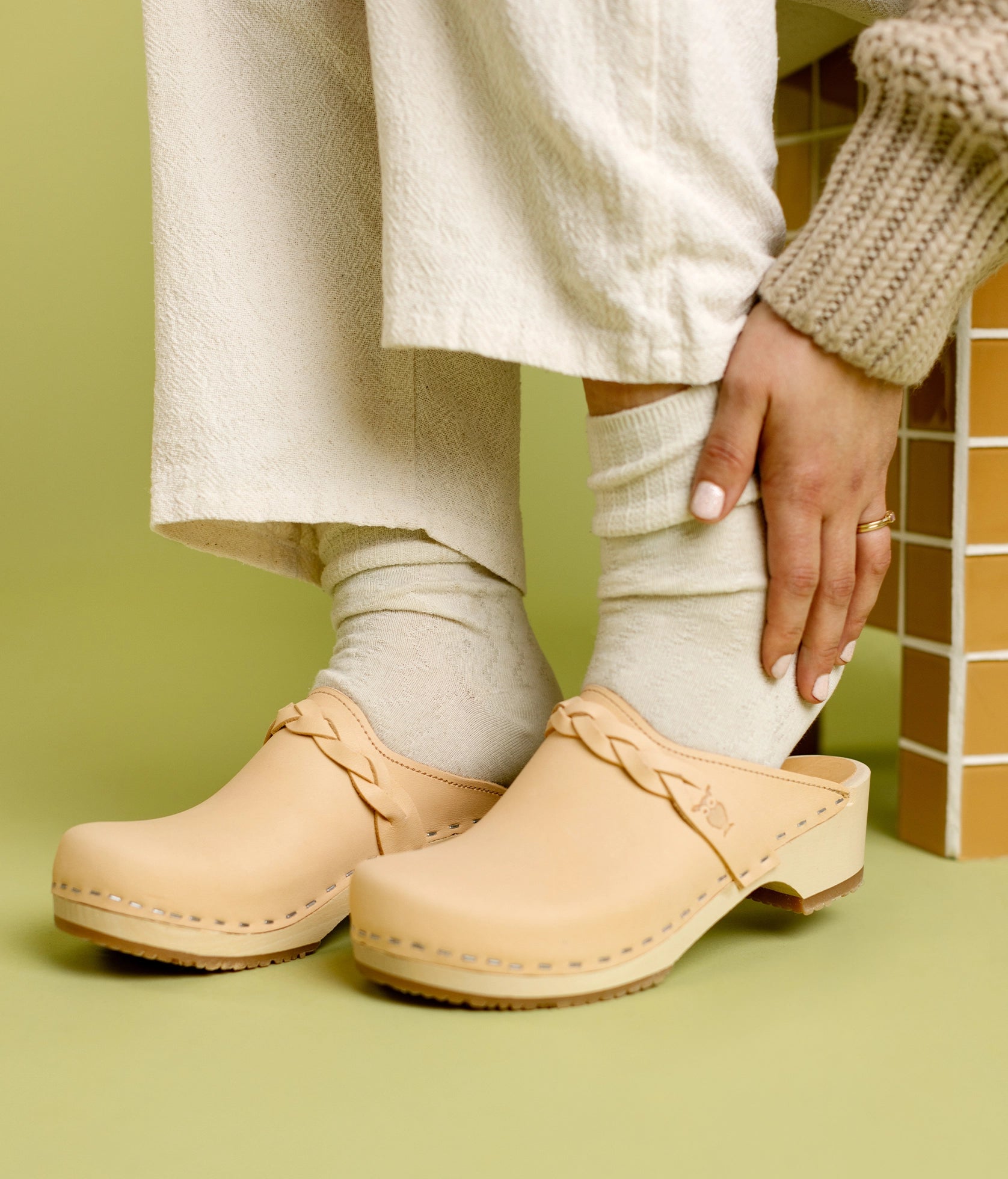 low heeled clog mules in ecru beige vegetable tanned leather with a braided strap stapled on a light wooden base