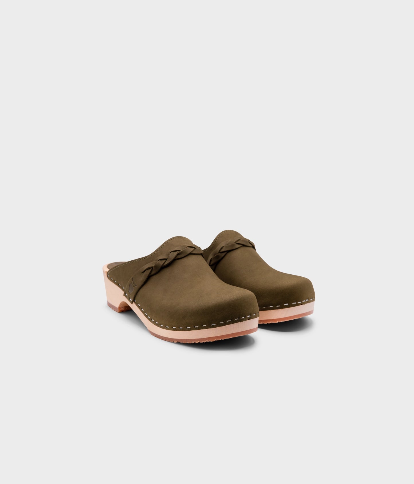 low heeled clog mules in olive green nubuck leather with a braided strap stapled on a light wooden base