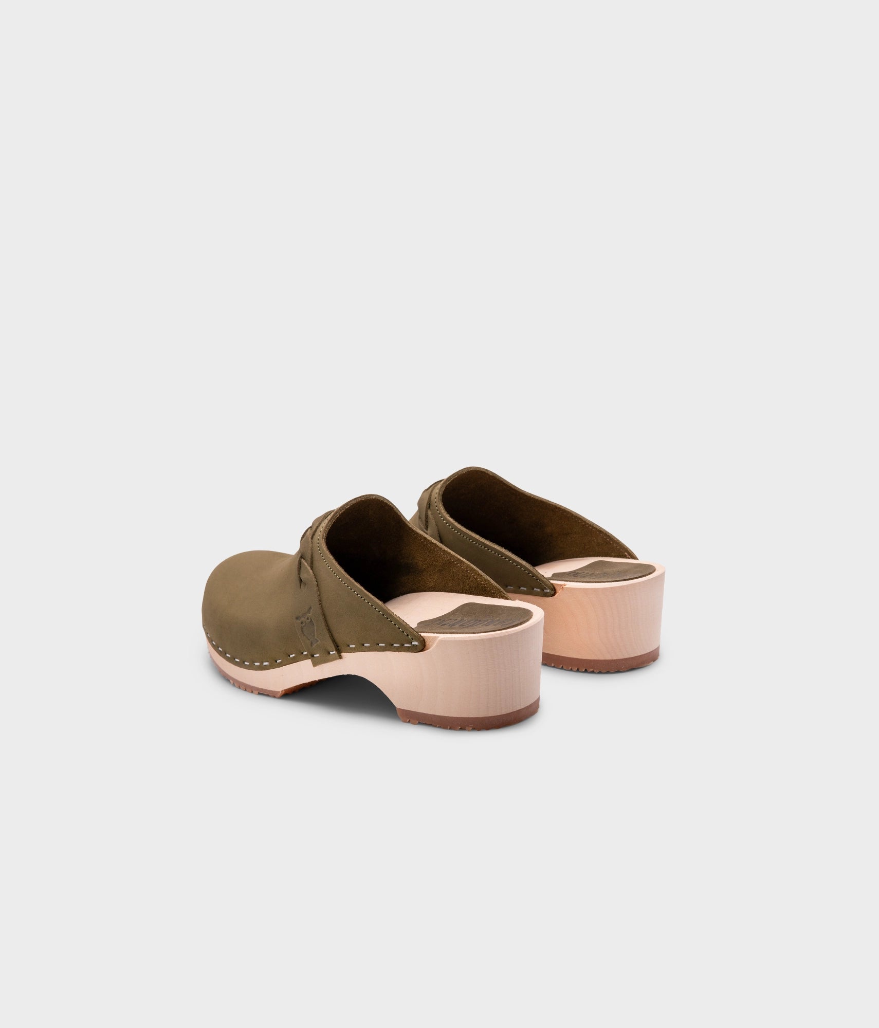 low heeled clog mules in olive green nubuck leather with a braided strap stapled on a light wooden base
