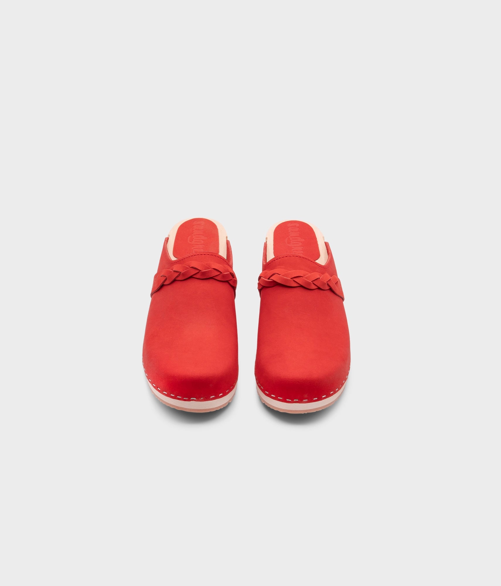 low heeled clog mules in red nubuck leather with a braided strap stapled on a light wooden base