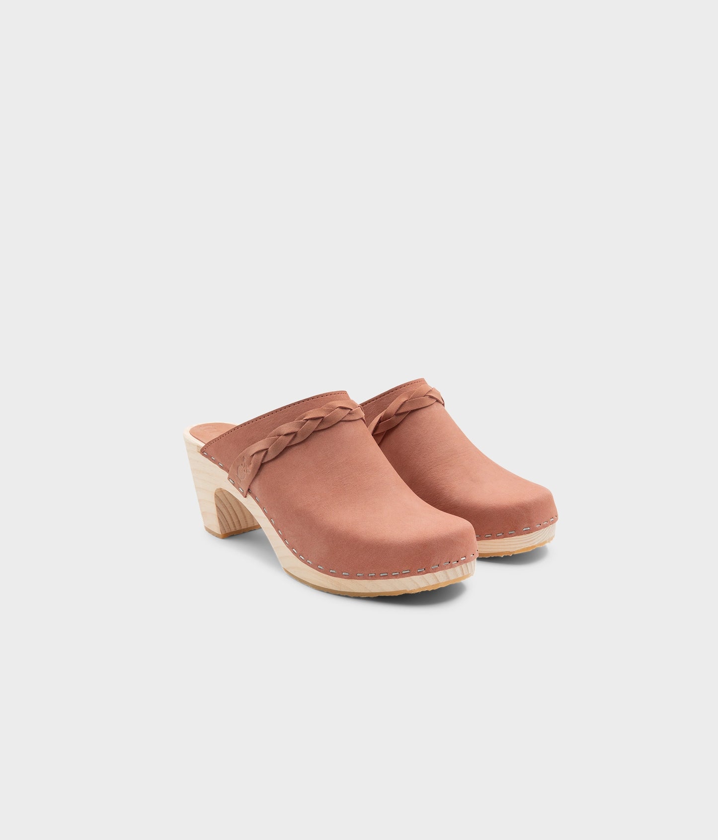 high rise heel braided clog mule in blush pink leather stapled on a light wooden base