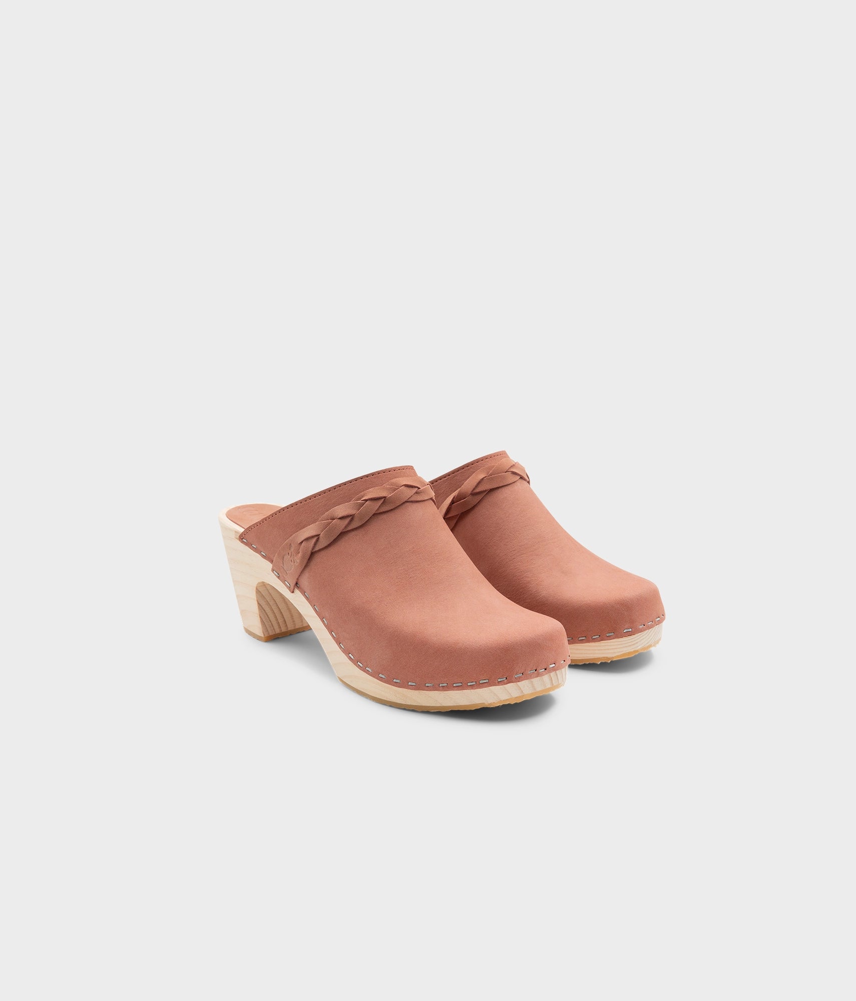 high rise heel braided clog mule in blush pink leather stapled on a light wooden base