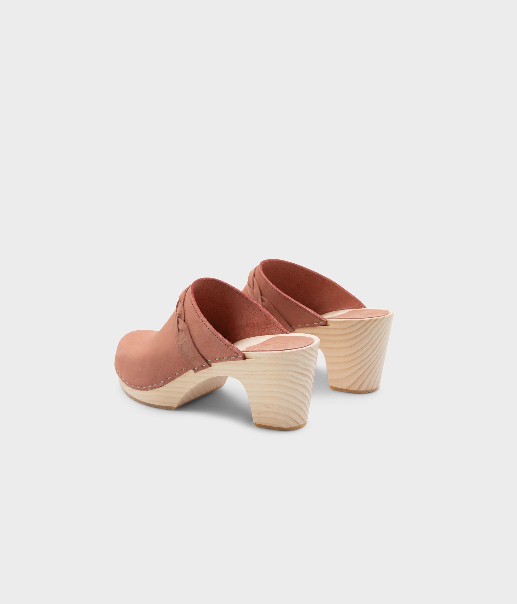 high rise heel braided clog mule in blush pink leather stapled on a light wooden base
