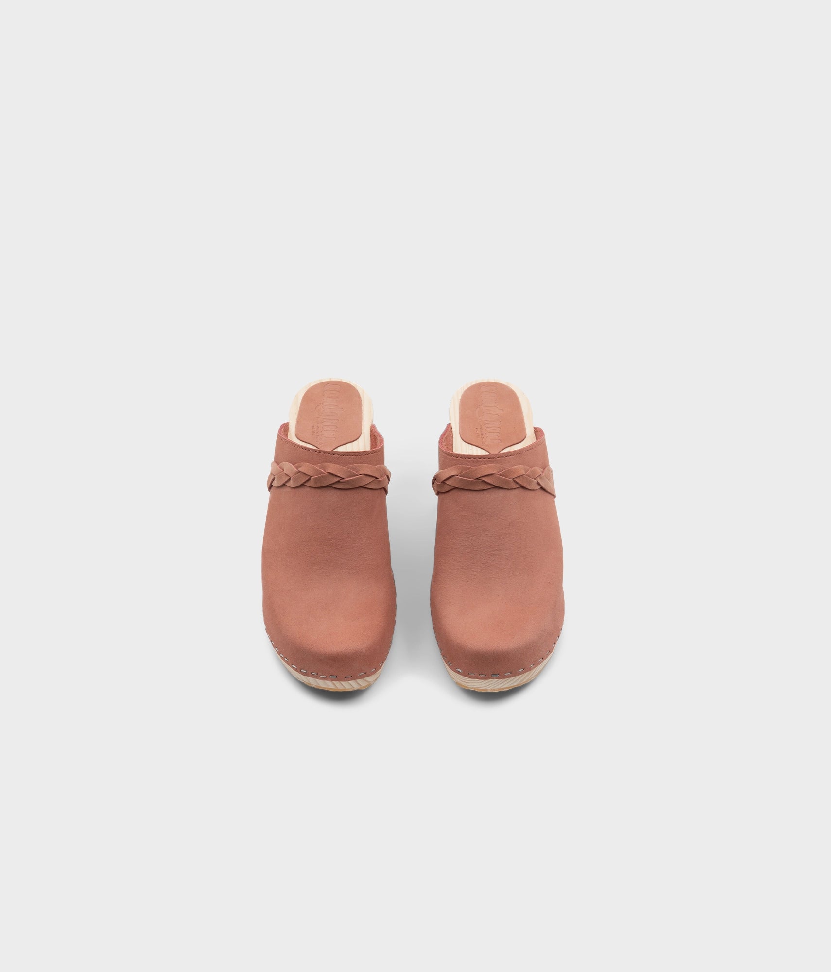high rise heel braided clog mule in blush pink leather stapled on a light wooden base