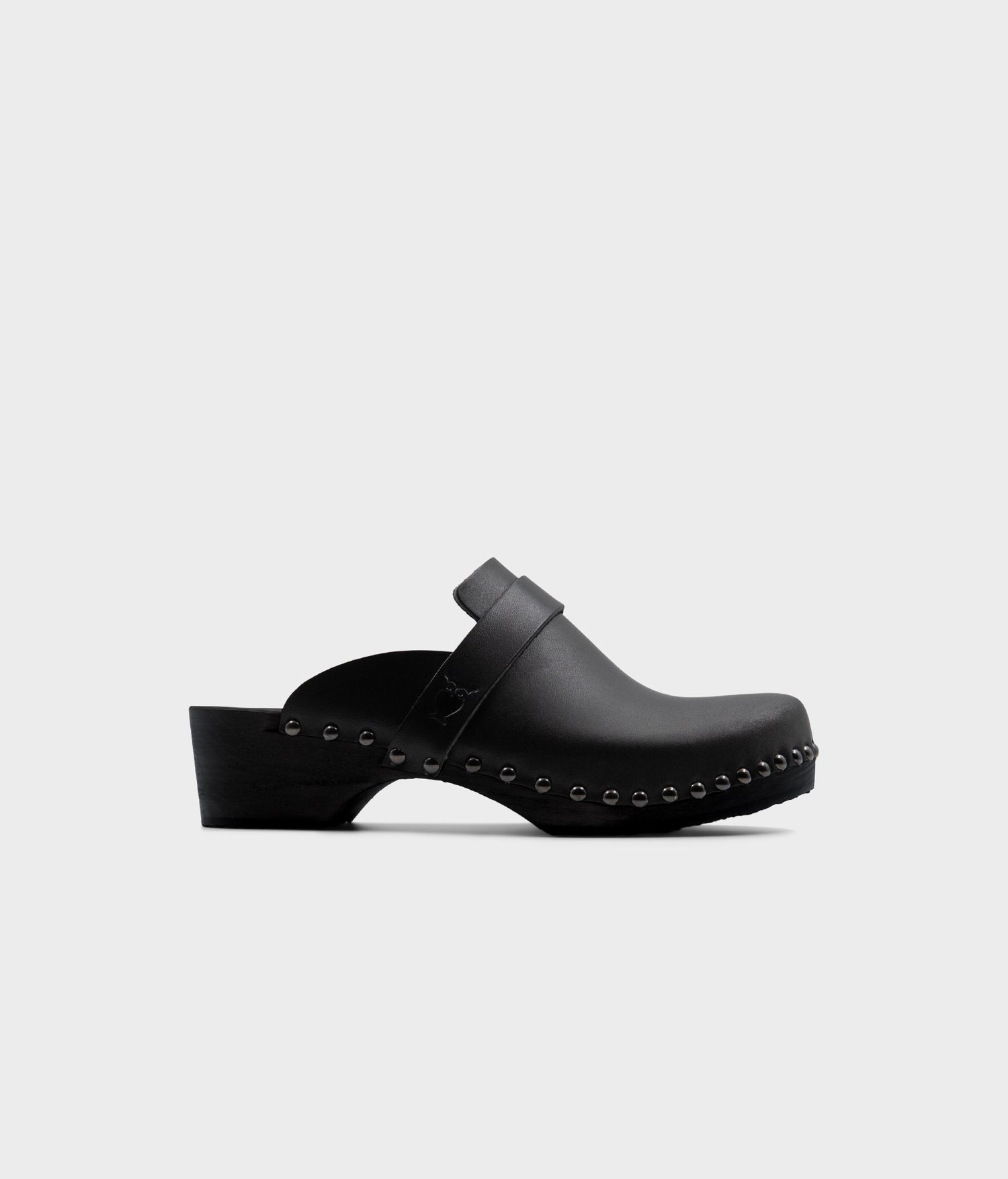 Classic low heeled clog mule in black vegetable tanden leather stapled with rustic studs on a black wooden base with a leather strap