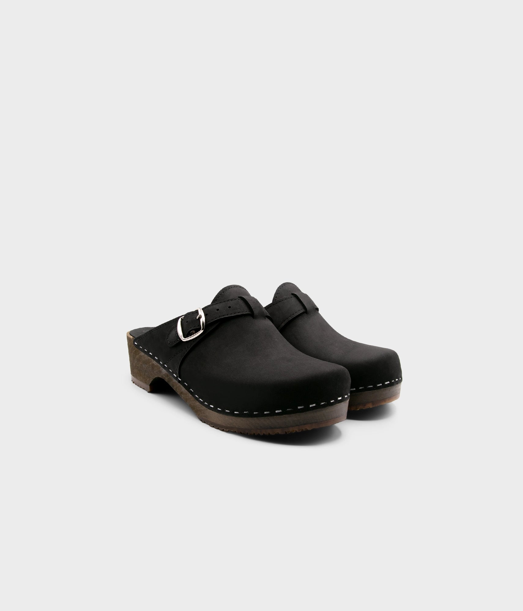 men's clog mule in black nubuck leather stapled on a dark wooden base with a silver buckle on top