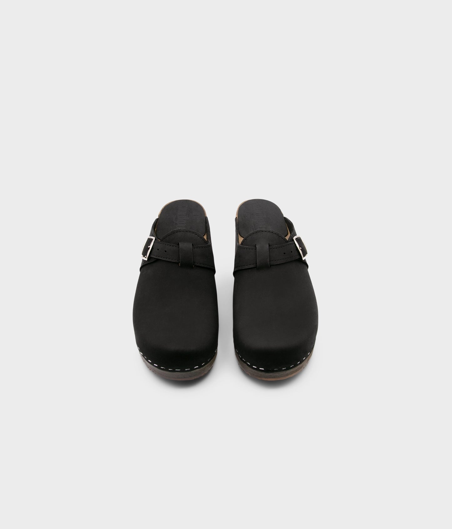 men's clog mule in black nubuck leather stapled on a dark wooden base with a silver buckle on top