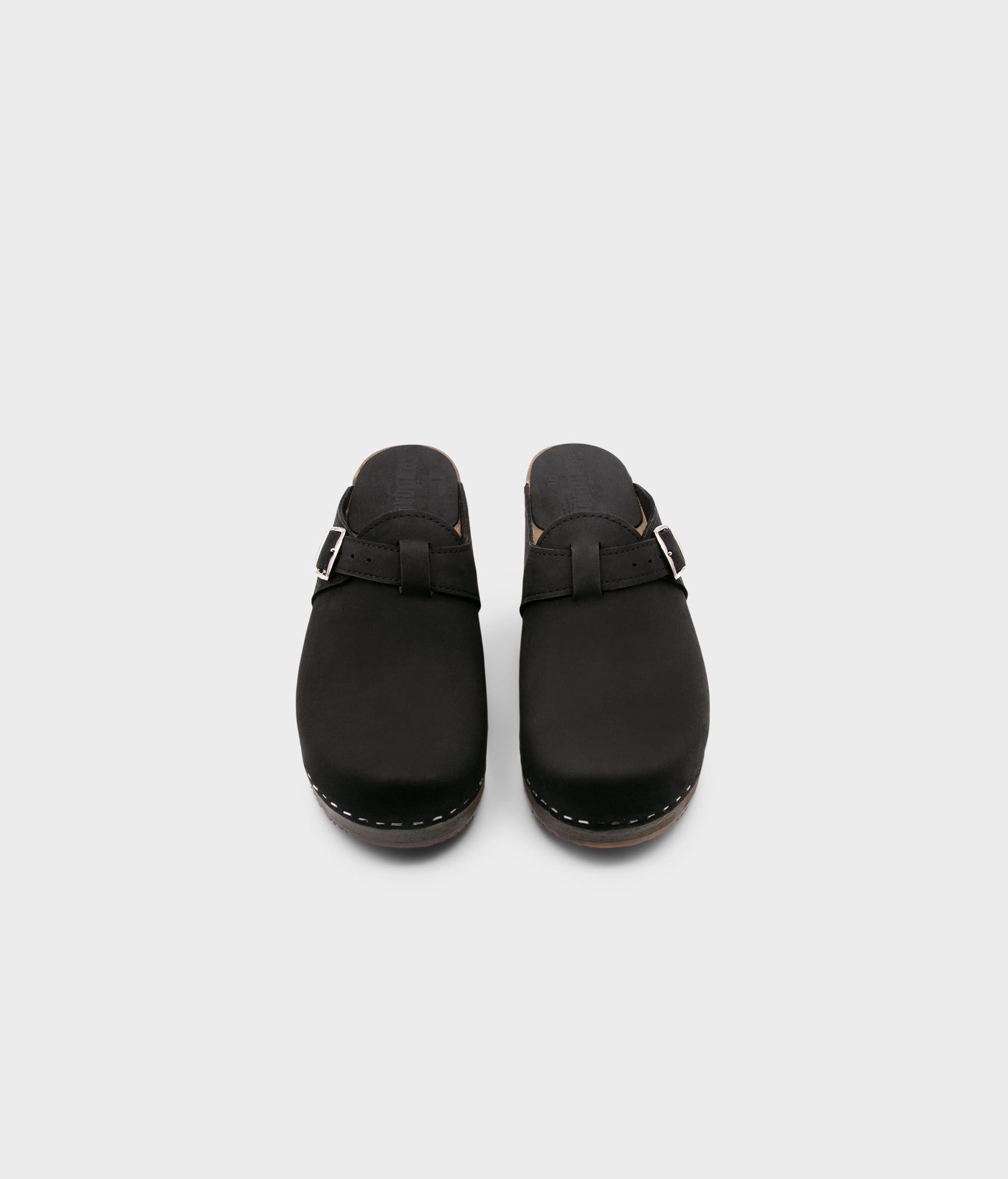 men's clog mule in black nubuck leather stapled on a dark wooden base with a silver buckle on top