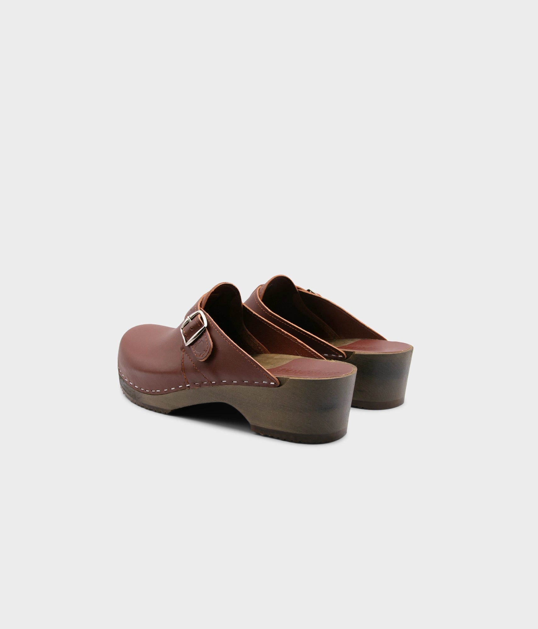 men's clog mule in cognac red vegetable tanned leather stapled on a dark wooden base with a silver buckle on top