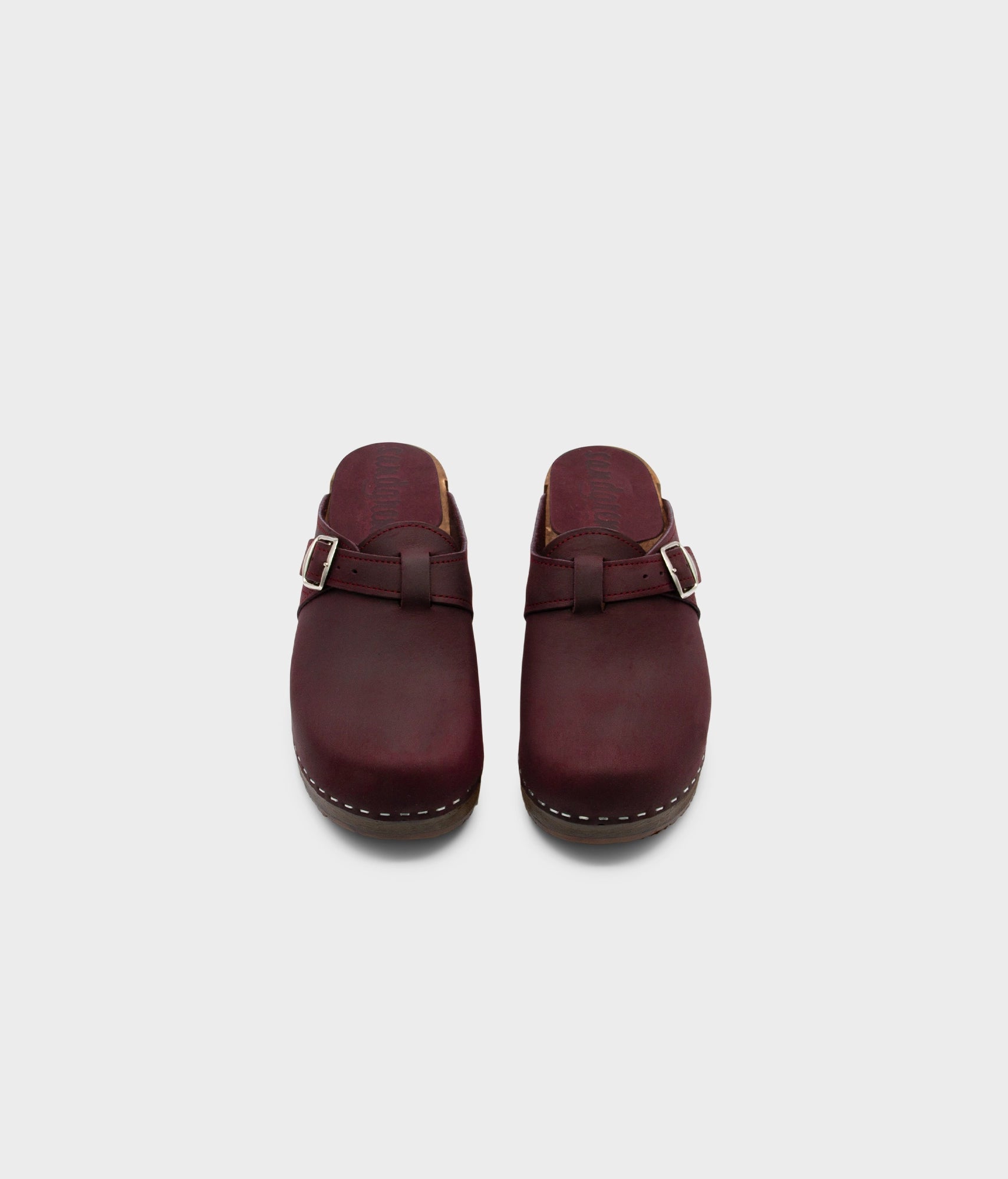 men's clog mule in purple plum nubuck leather stapled on a dark wooden base with a silver buckle on top