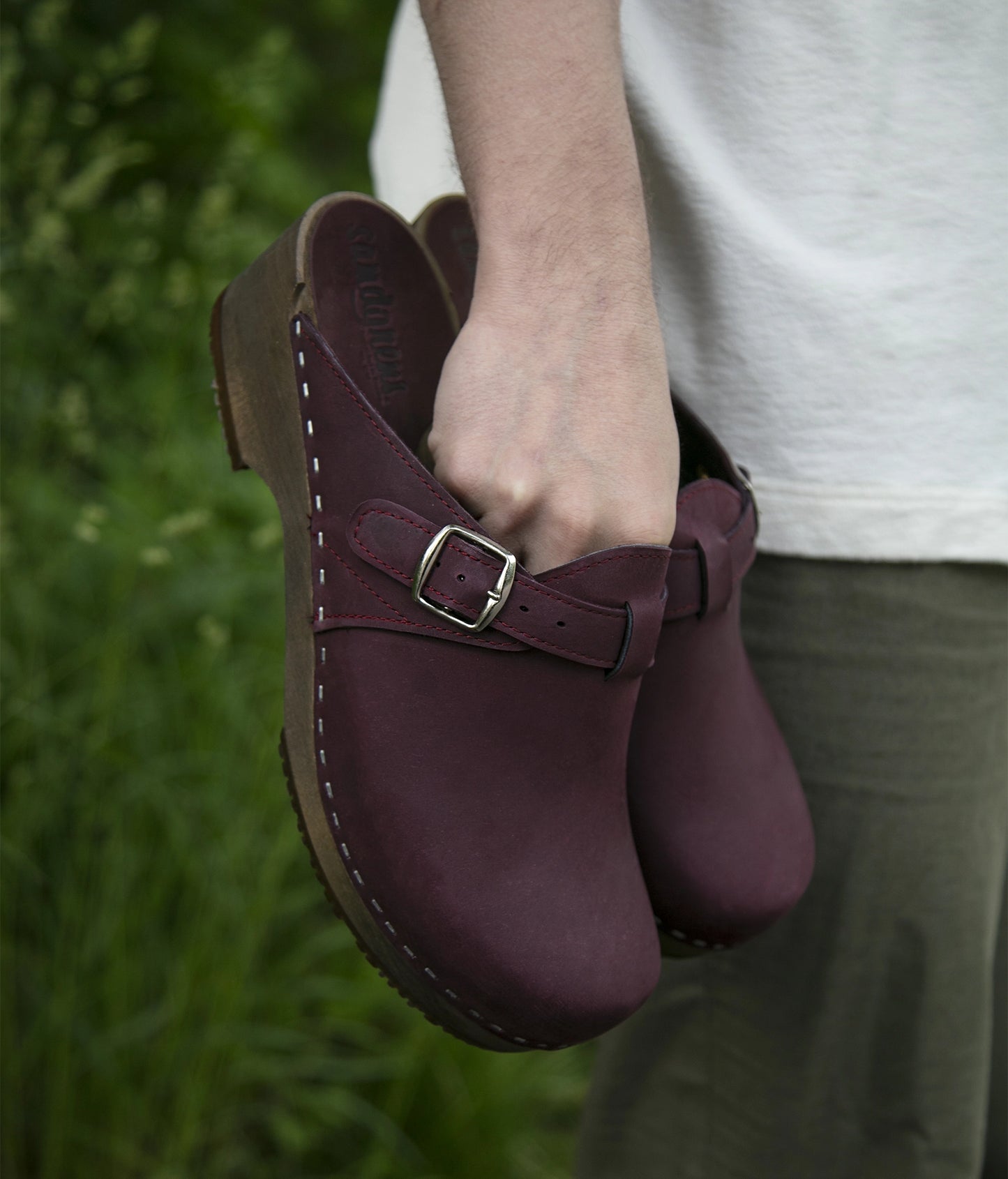 men's clog mule in purple plum nubuck leather stapled on a dark wooden base with a silver buckle on top