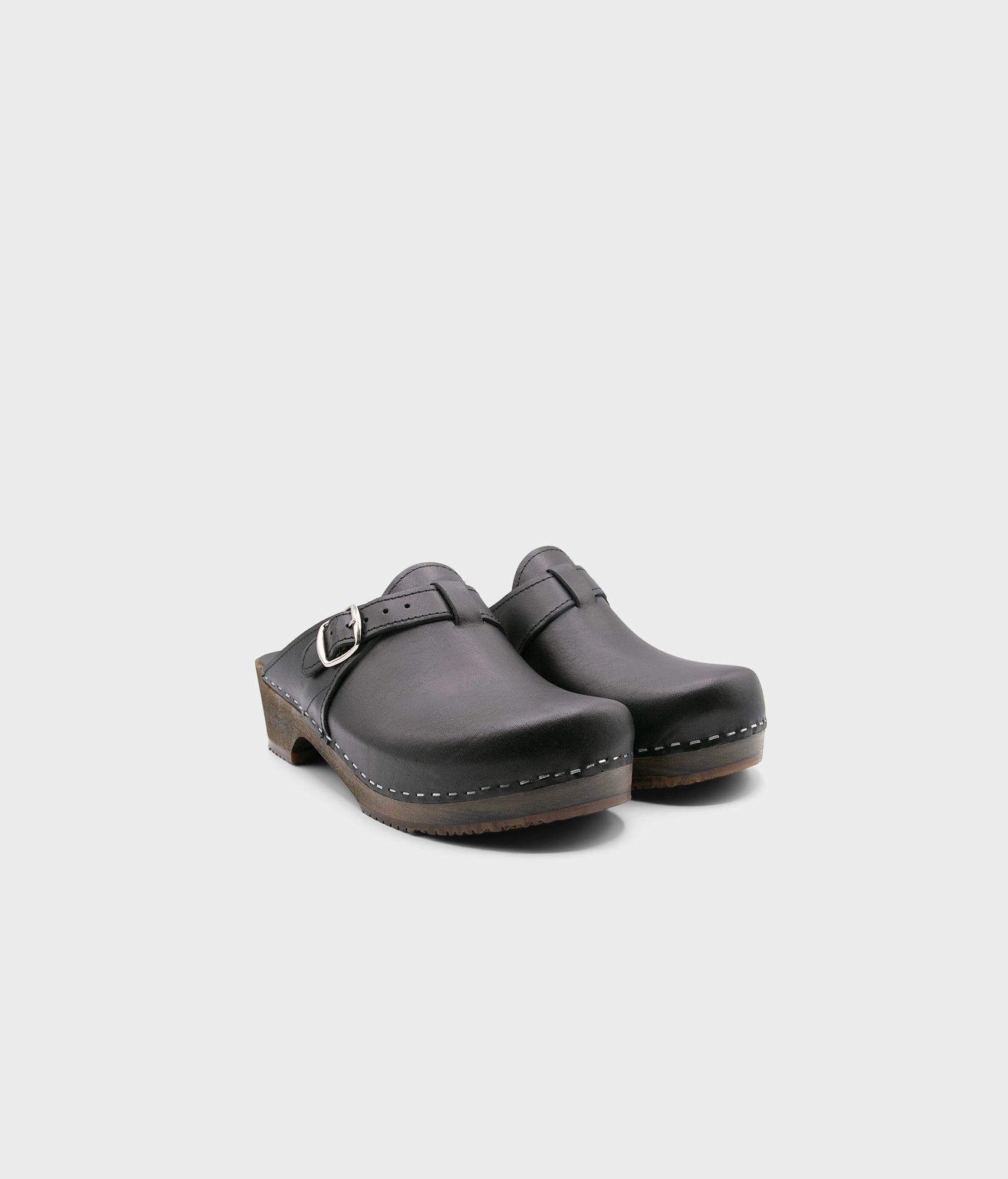 men's clog mule in black vegetable tanned leather stapled on a dark wooden base with a silver buckle on top