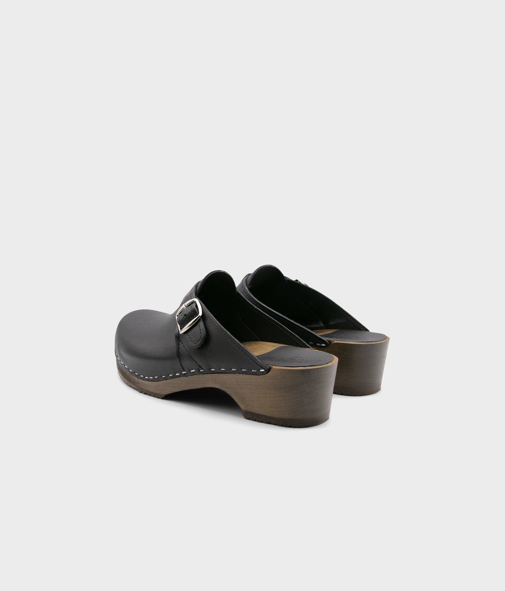 men's clog mule in black vegetable tanned leather stapled on a dark wooden base with a silver buckle on top