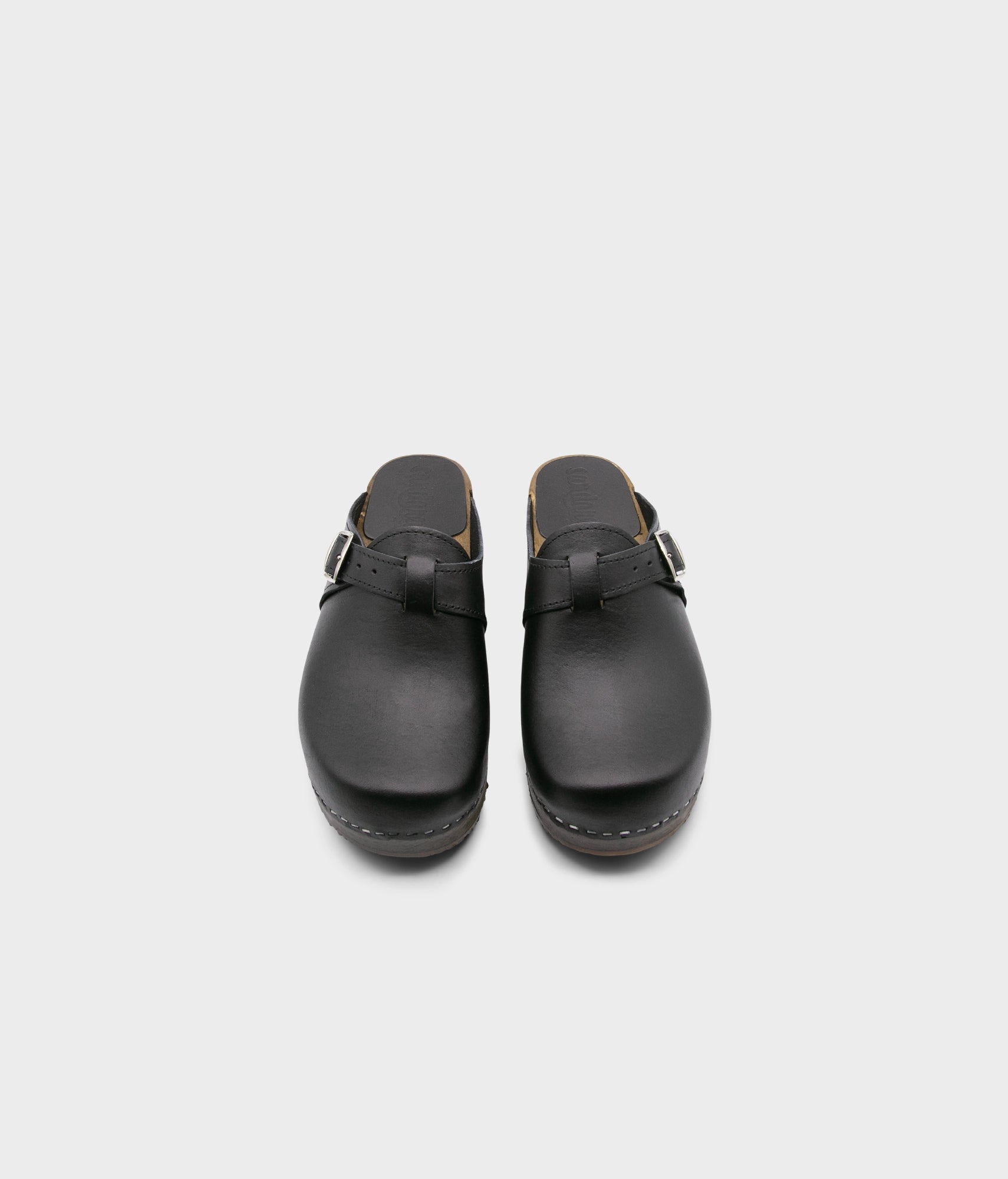 men's clog mule in black vegetable tanned leather stapled on a dark wooden base with a silver buckle on top