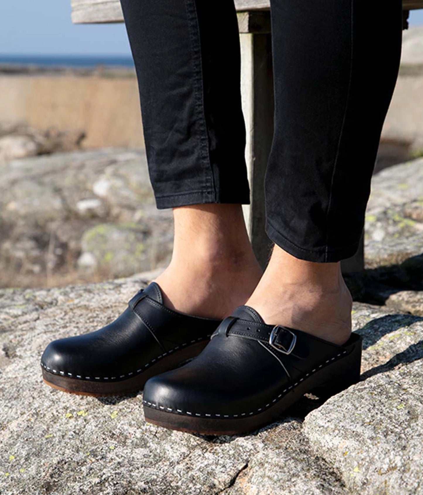 men's clog mule in black vegetable tanned leather stapled on a dark wooden base with a silver buckle on top