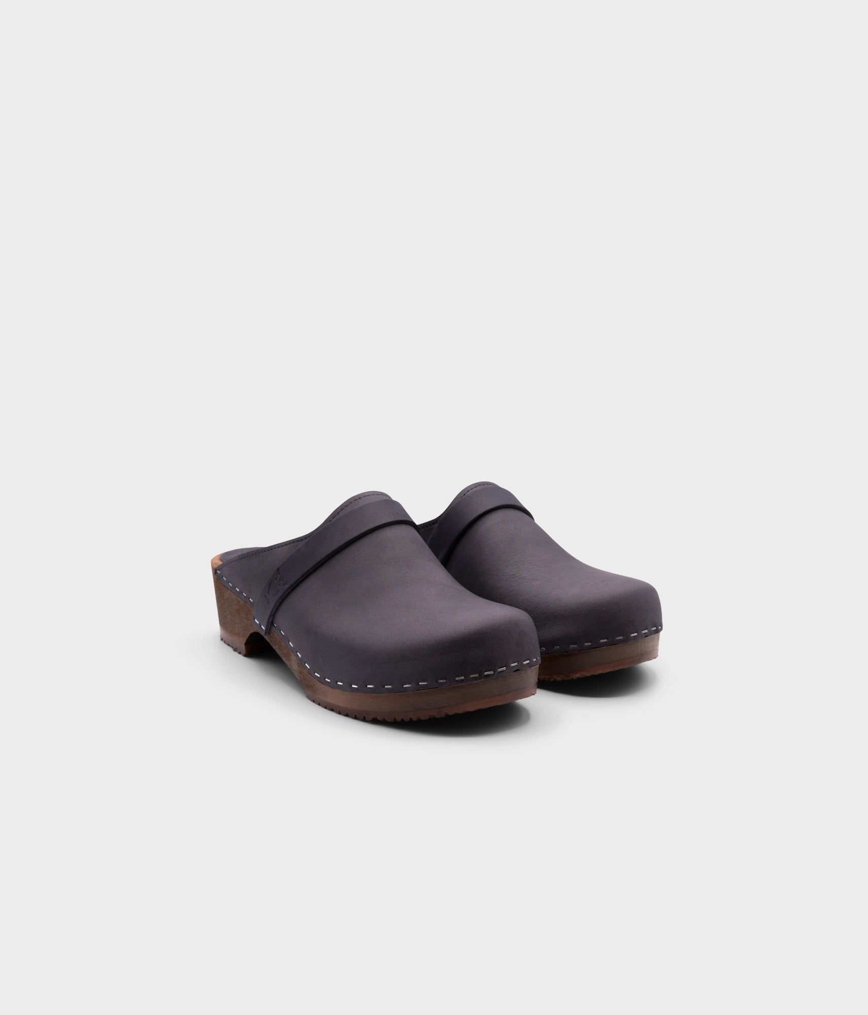 low heeled classic clog mules in navy blue nubuck leather stapled on a dark wooden base