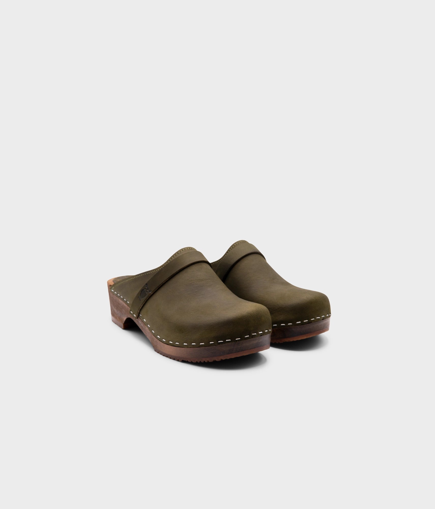low heeled classic clog mules in olive green nubuck leather stapled on a dark wooden base