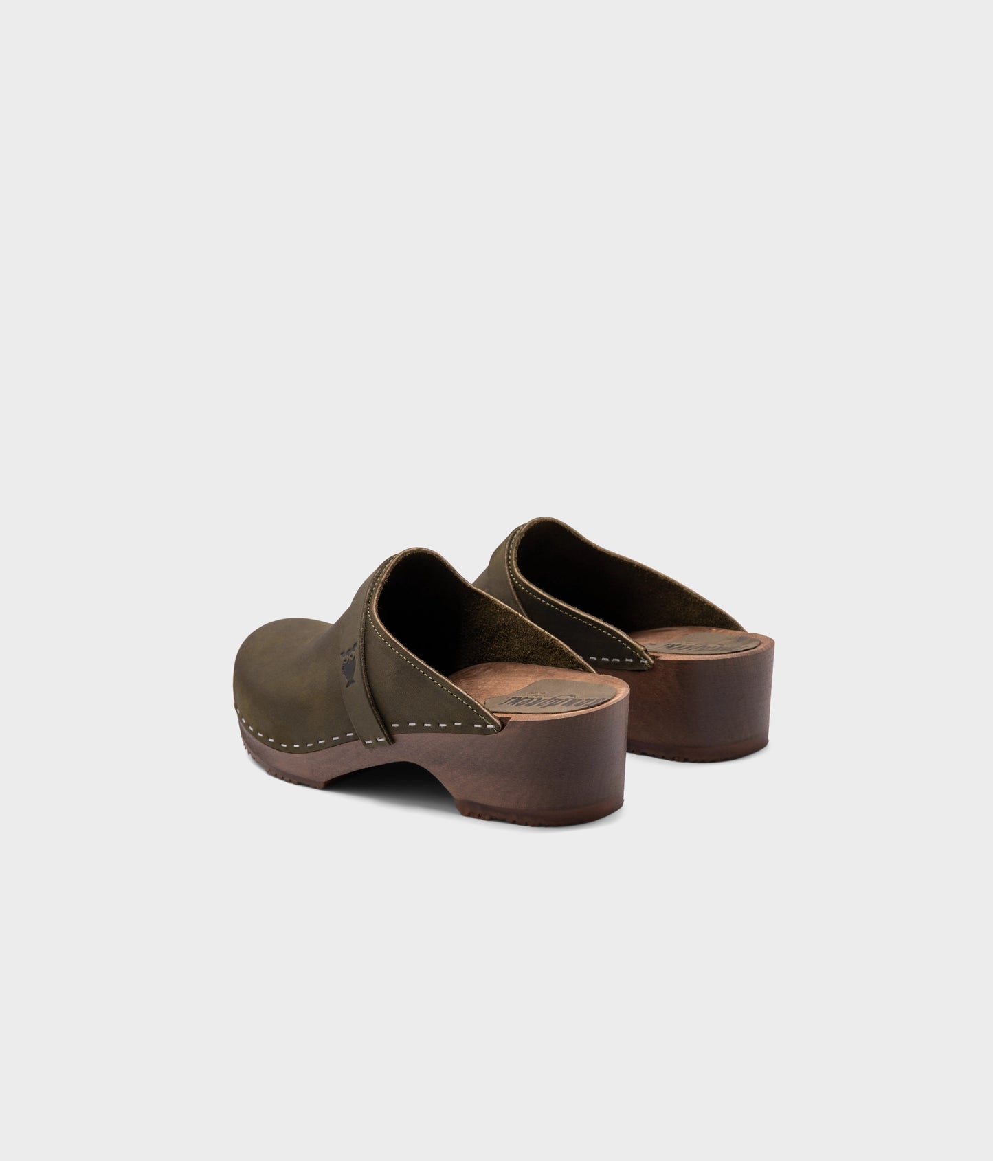 low heeled classic clog mules in olive green nubuck leather stapled on a dark wooden base
