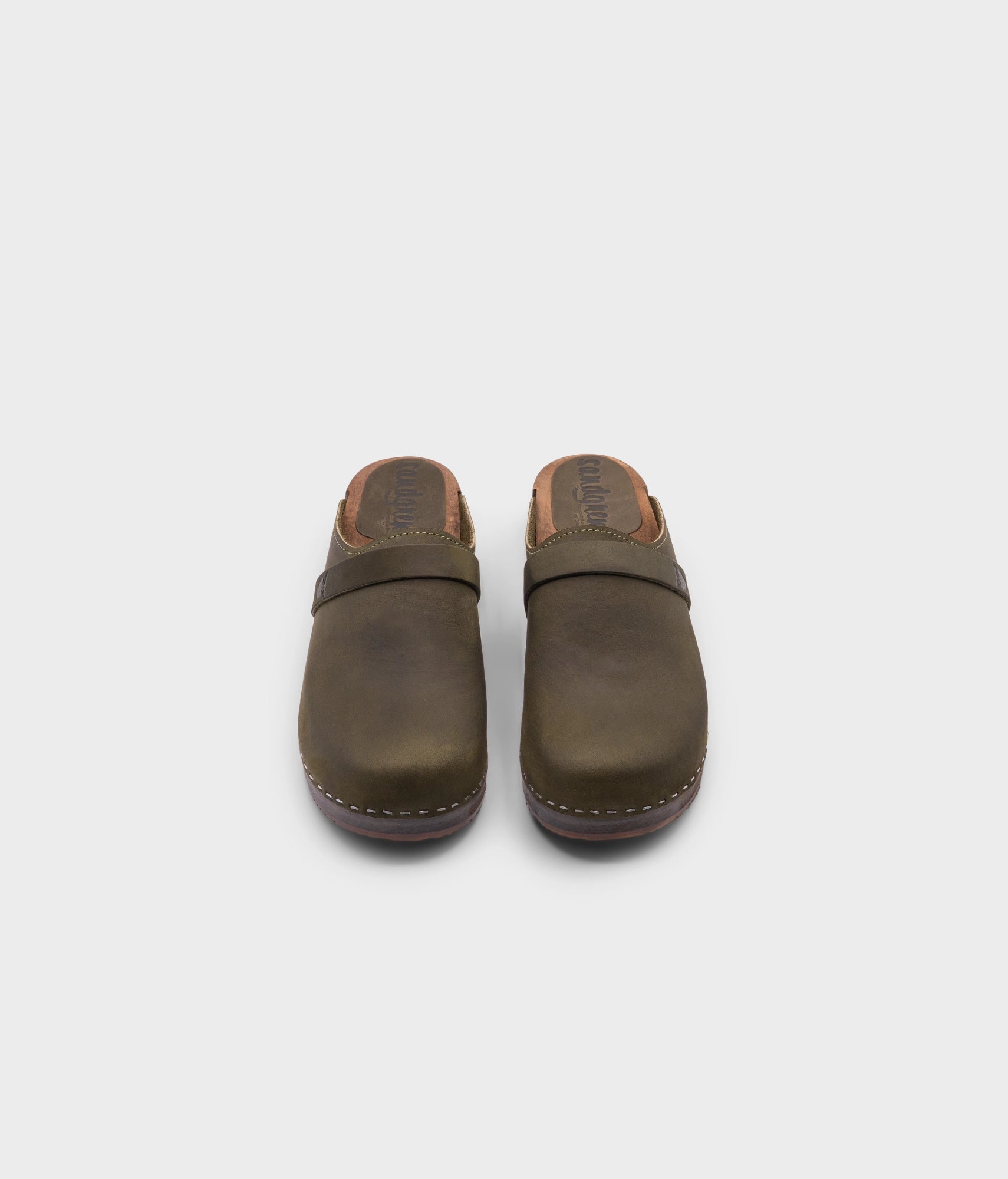 low heeled classic clog mules in olive green nubuck leather stapled on a dark wooden base