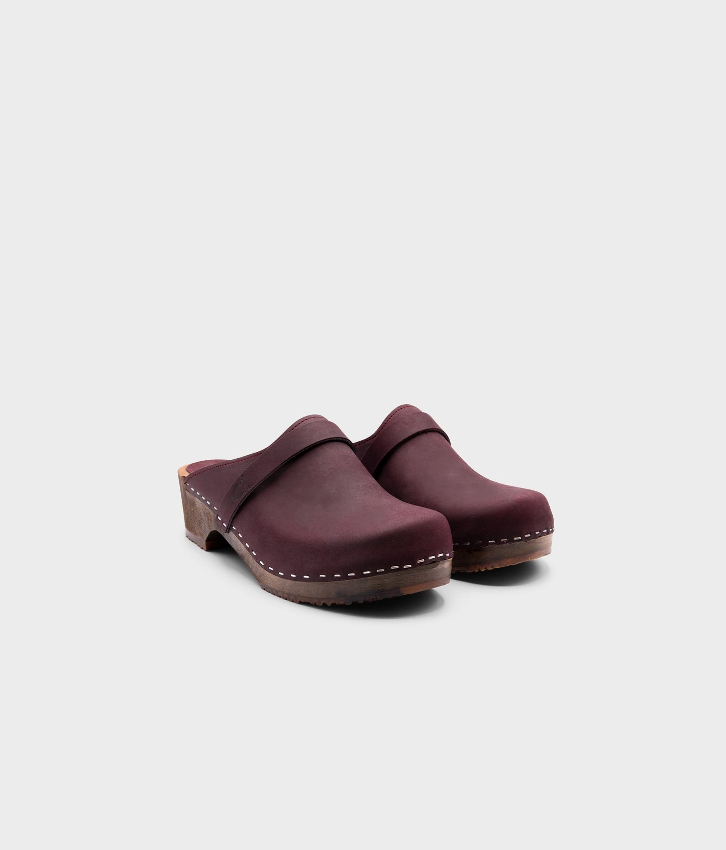 low heeled classic clog mules in plum purple nubuck leather stapled on a dark wooden base