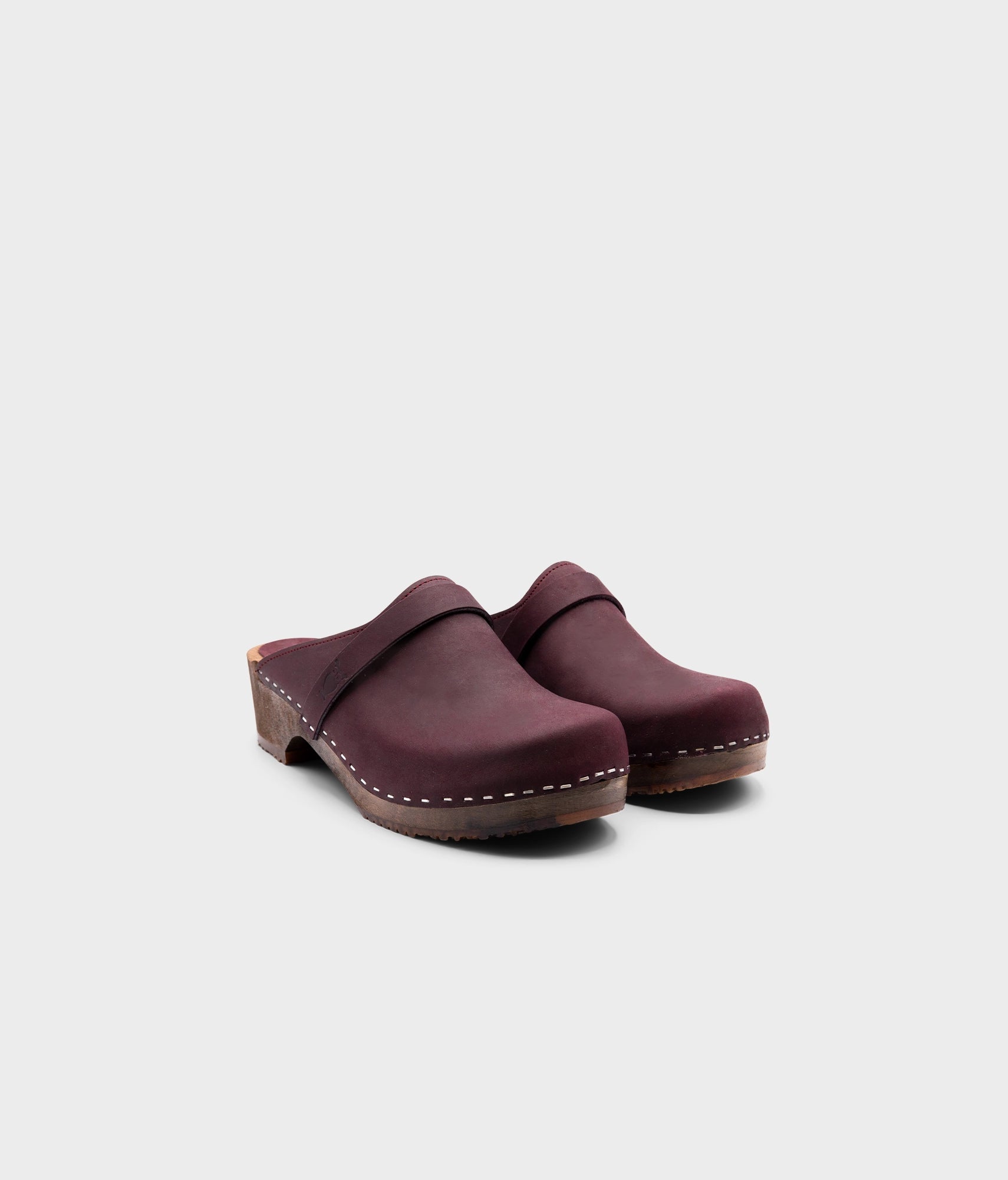 low heeled classic clog mules in plum purple nubuck leather stapled on a dark wooden base