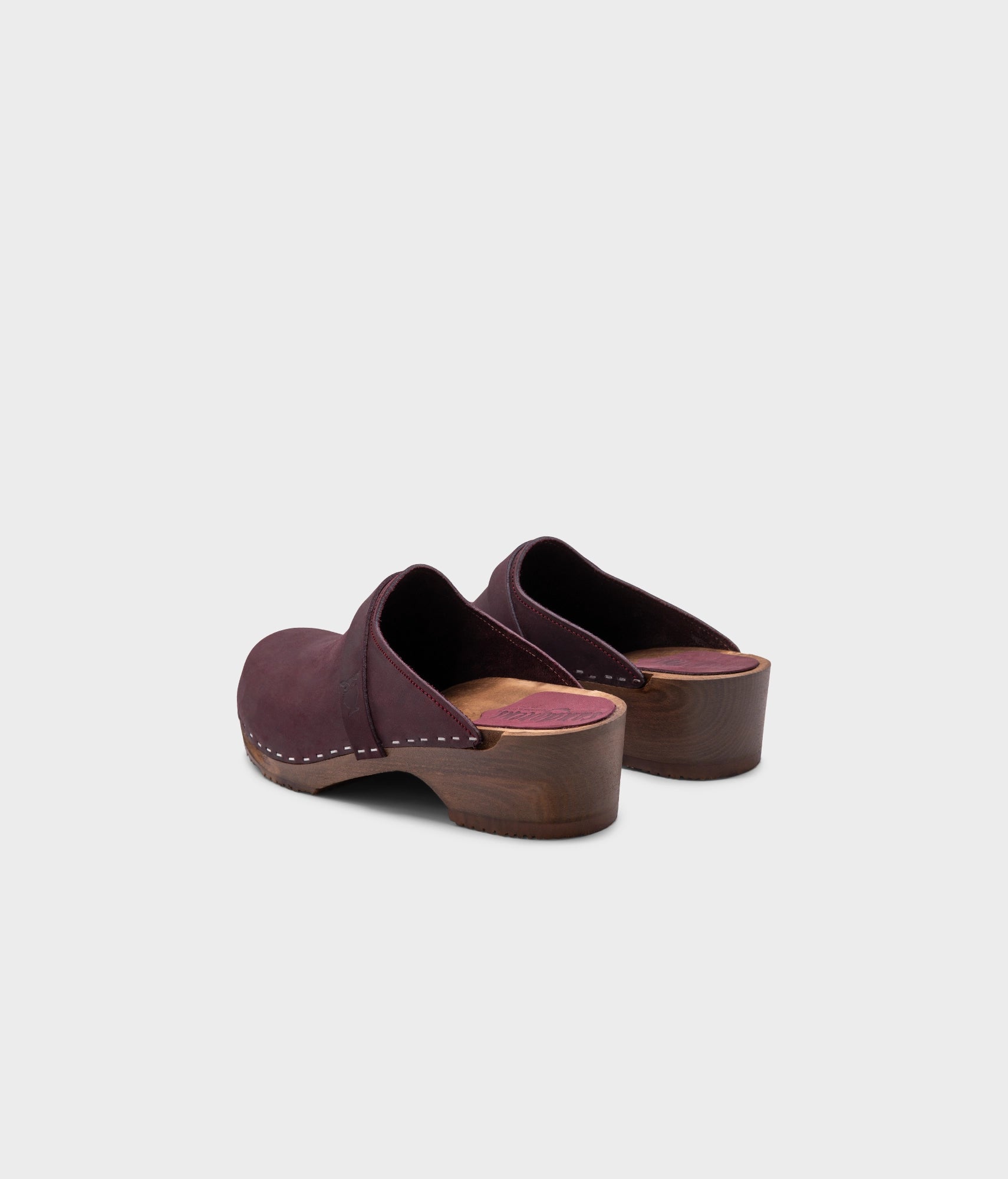 low heeled classic clog mules in plum purple nubuck leather stapled on a dark wooden base
