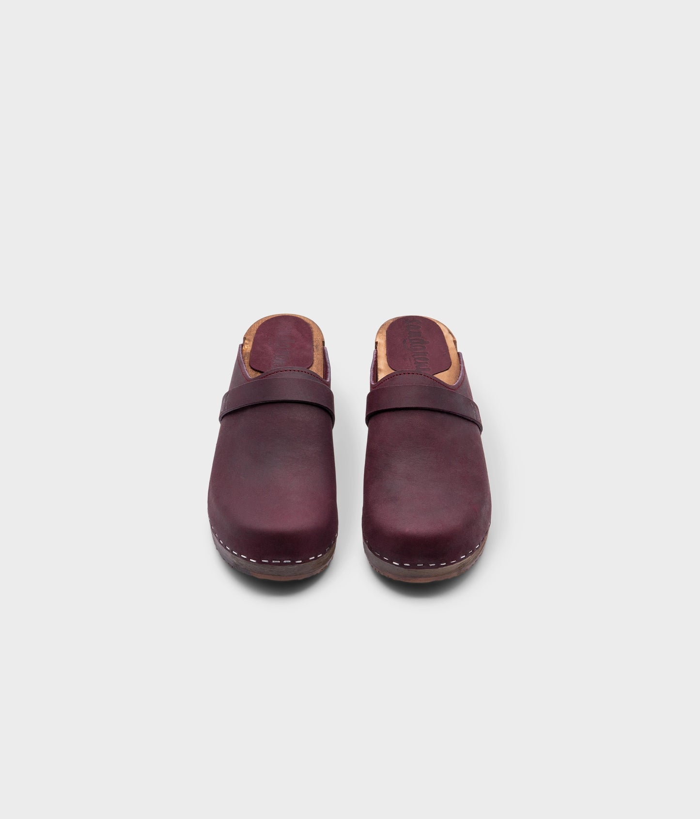 low heeled classic clog mules in plum purple nubuck leather stapled on a dark wooden base