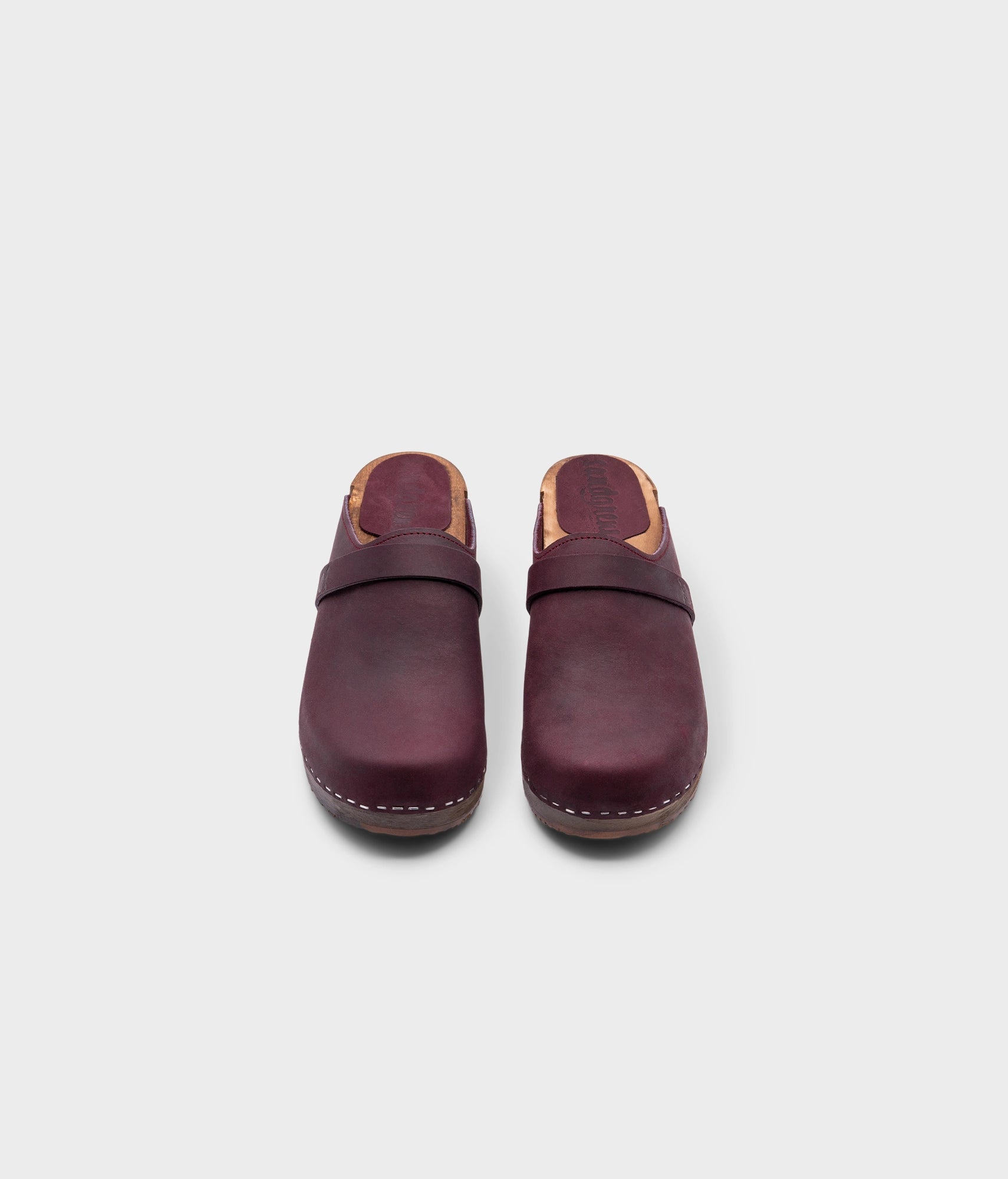 low heeled classic clog mules in plum purple nubuck leather stapled on a dark wooden base