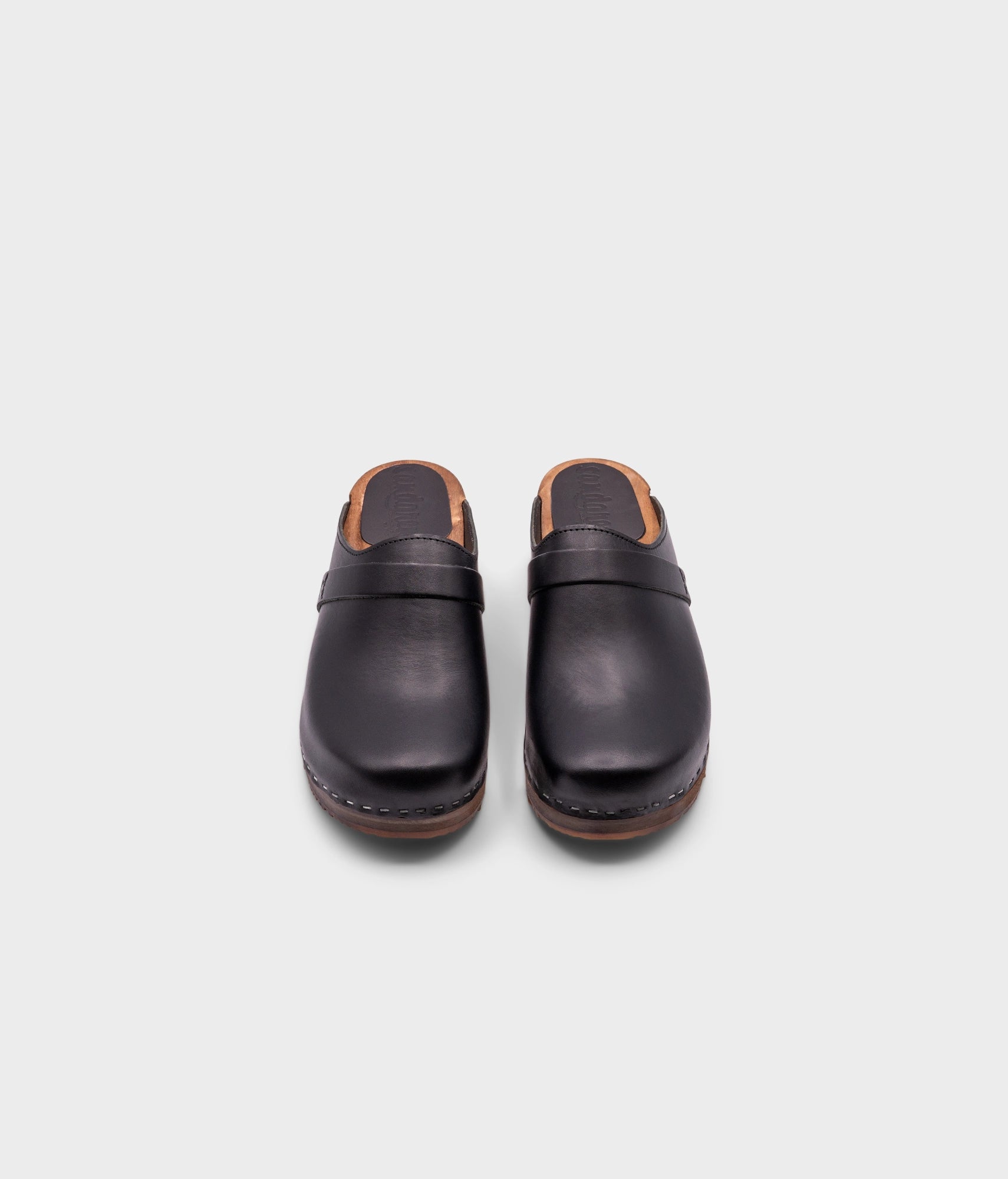 low heeled classic clog mules in black vegetable tanned leather stapled on a light wooden base