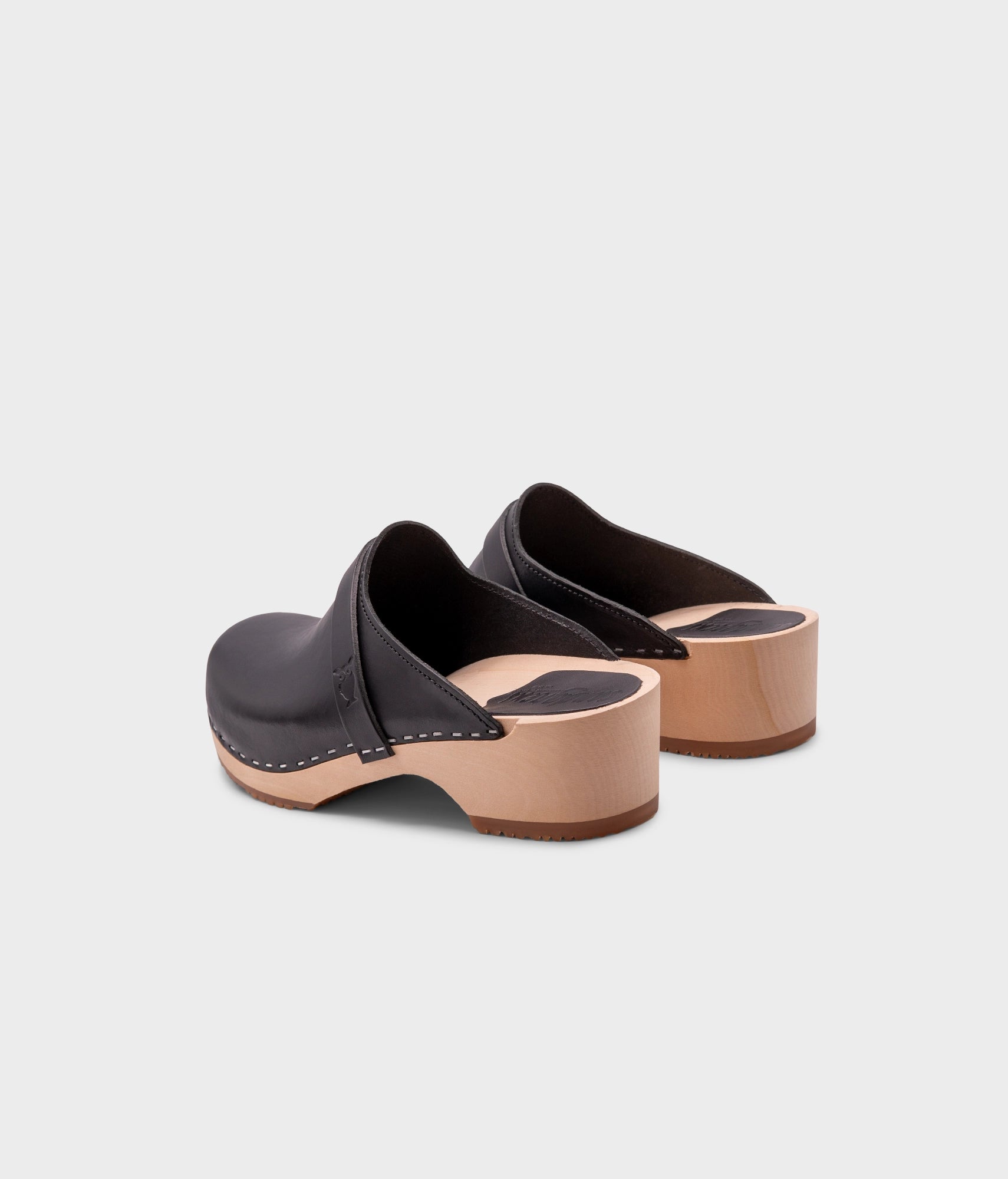 low heeled classic clog mules in black vegetable tanned leather stapled on a light wooden base