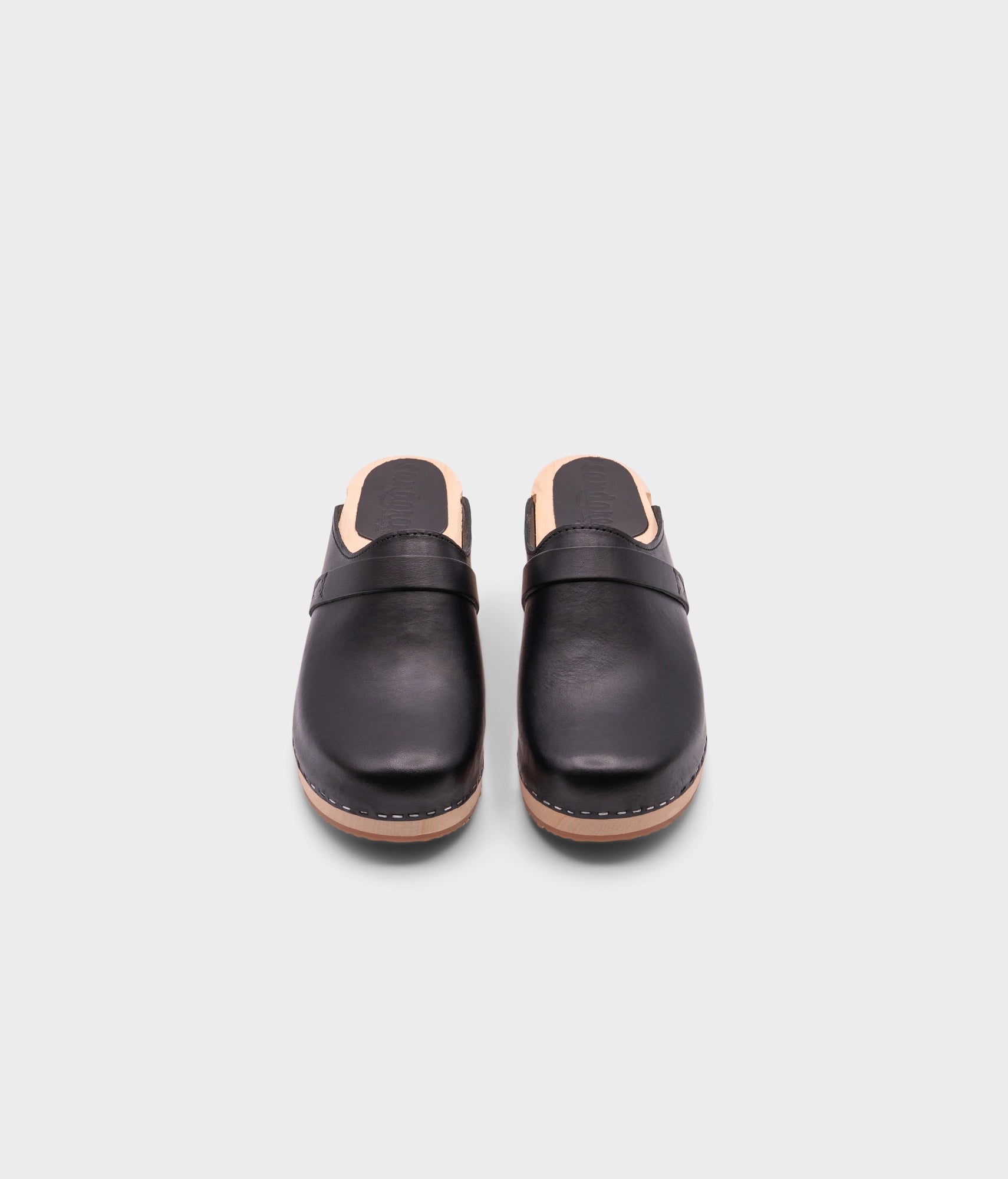 low heeled classic clog mules in black vegetable tanned leather stapled on a light wooden base
