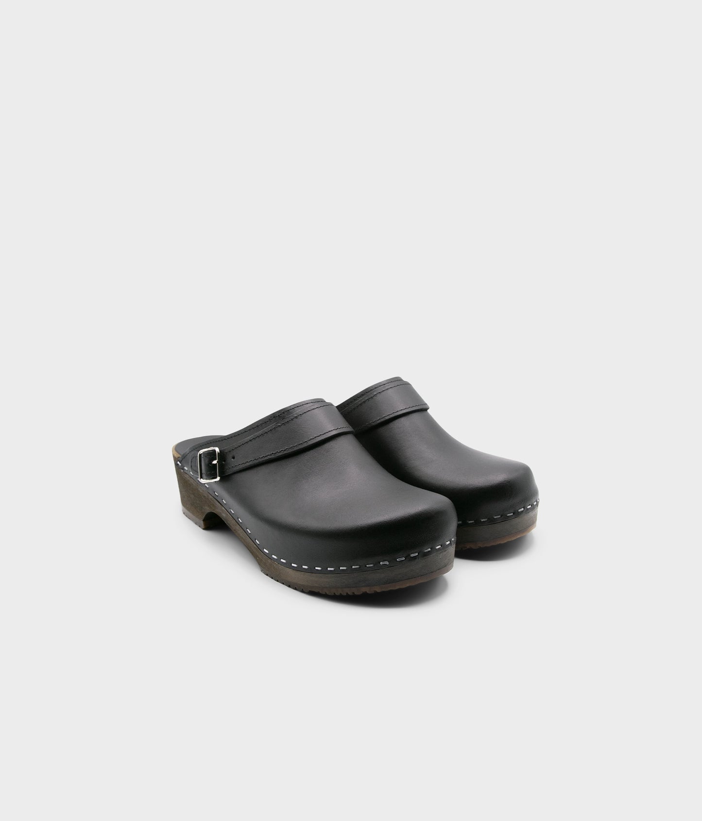men's low heeled clog mules in black vegetable tanned leather stapled on a dark wooden base with a sling back